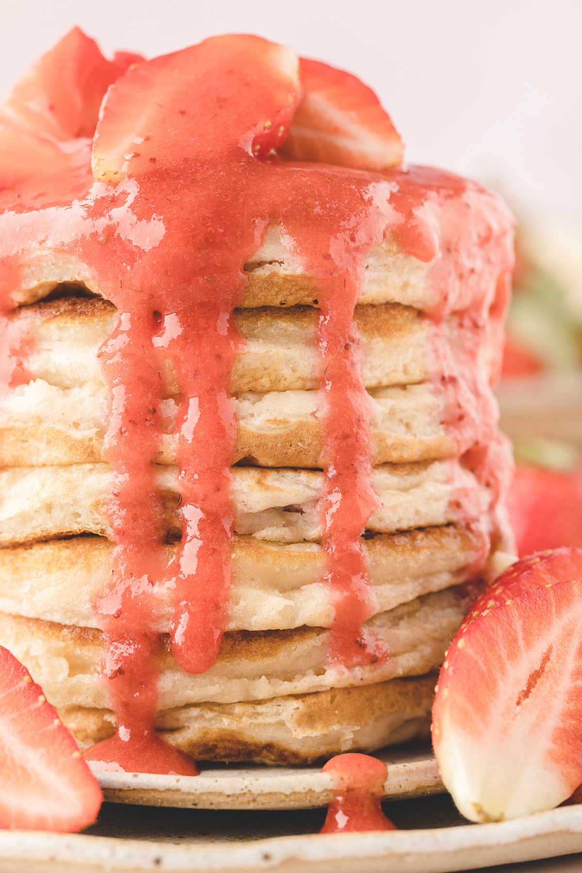 Fresh Strawberry Buttermilk Pancakes Fresh strawberry buttermilk pancakes stacked high with glossy strawberry sauce dripping down the sides and fresh strawberries around the plate.