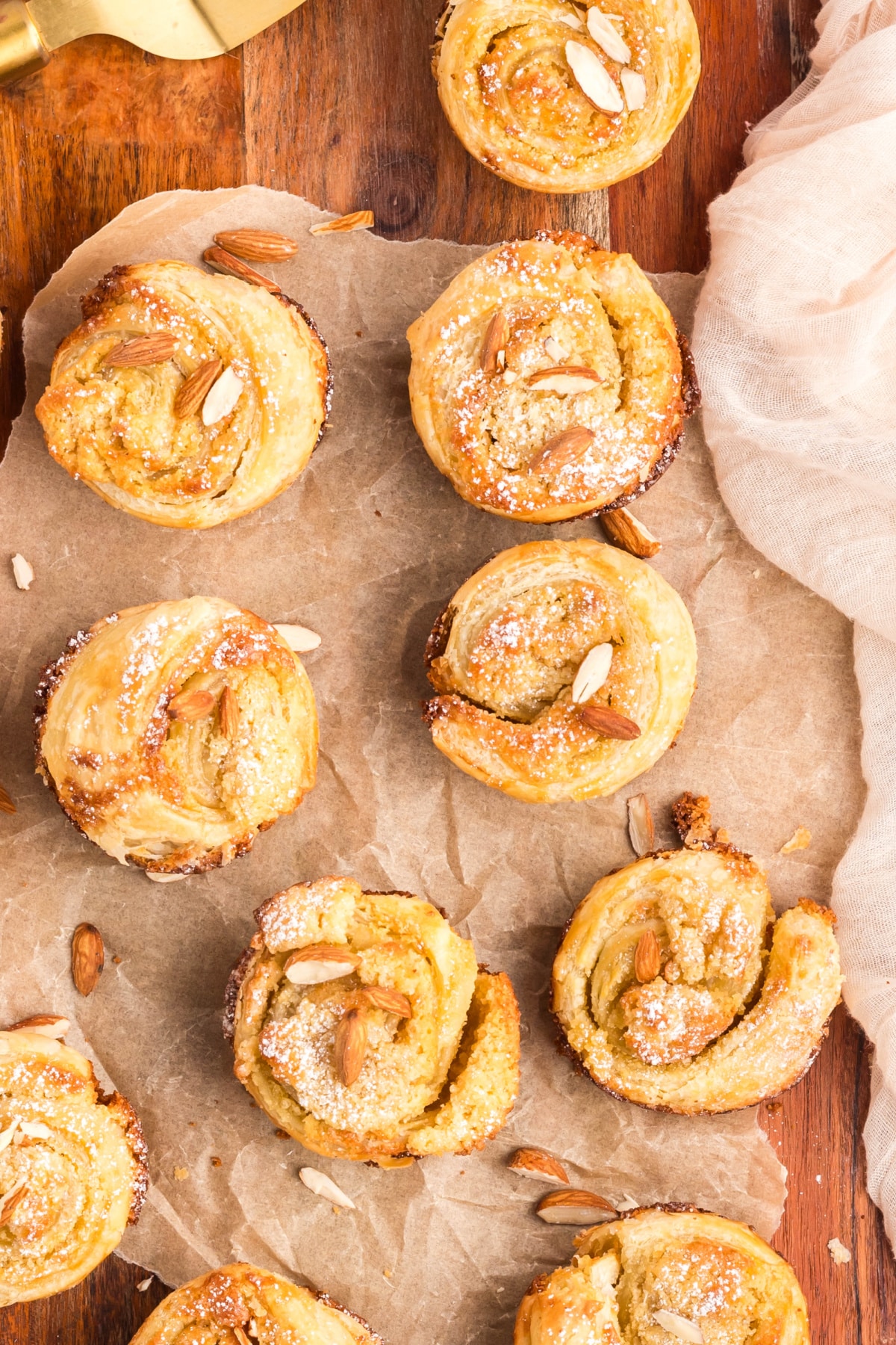 a batch of almond cruffins Top-down view of a batch of golden brown cruffins arranged closely together, showing their swirled tops.