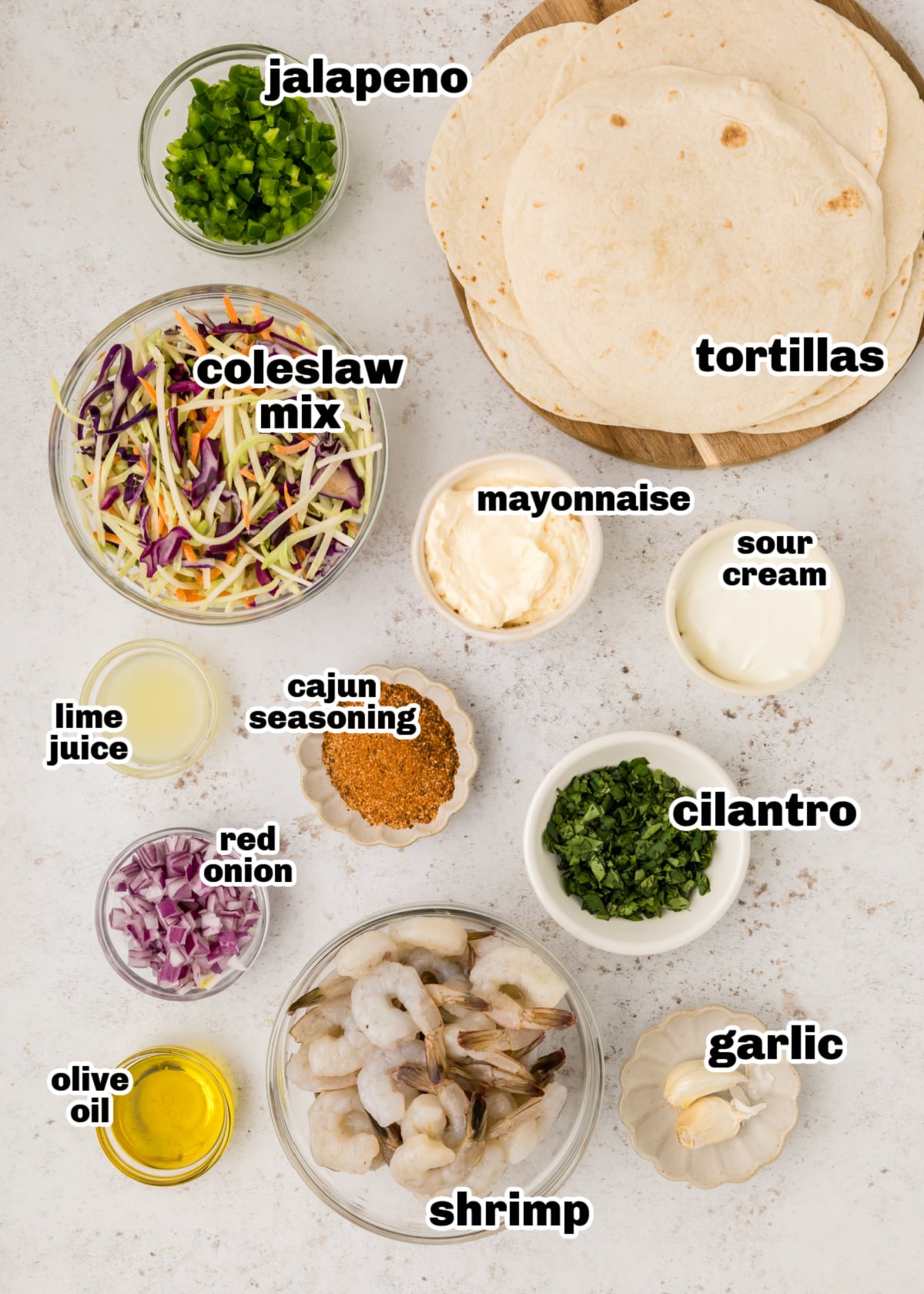 Ingredients laid out for cajun shrimp tacos, including shrimp, slaw mix, spices, and tortillas