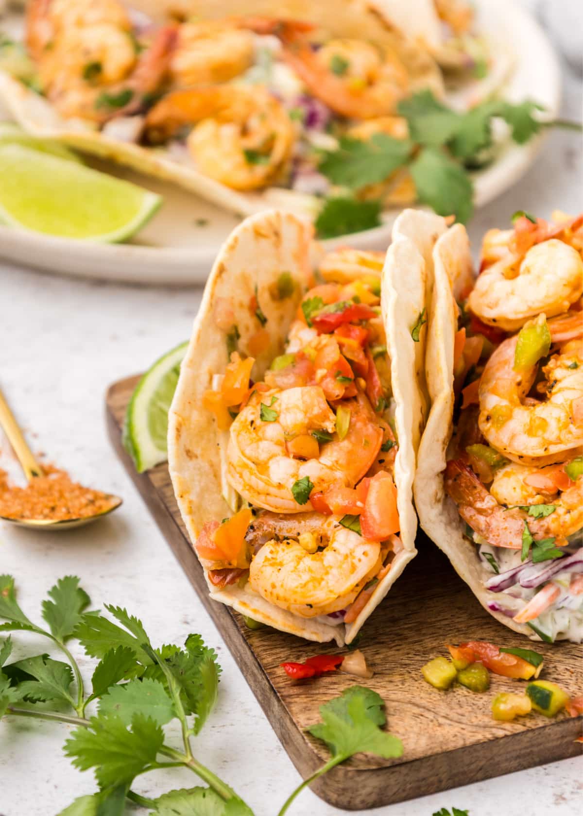 Two filled Cajun shrimp tacos on a wooden cutting board, showing shrimp and slaw inside