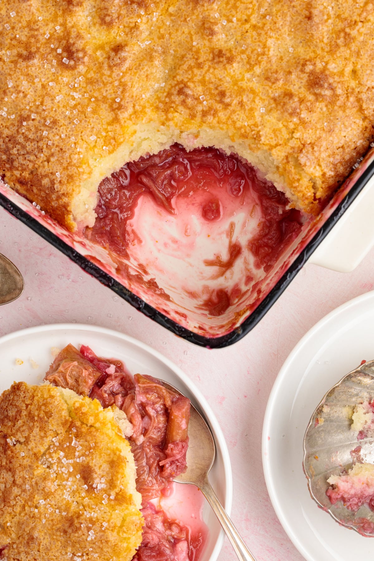 Overhead view of cobbler with a scoop missing and a plated serving nearby, topped with vanilla ice cream.