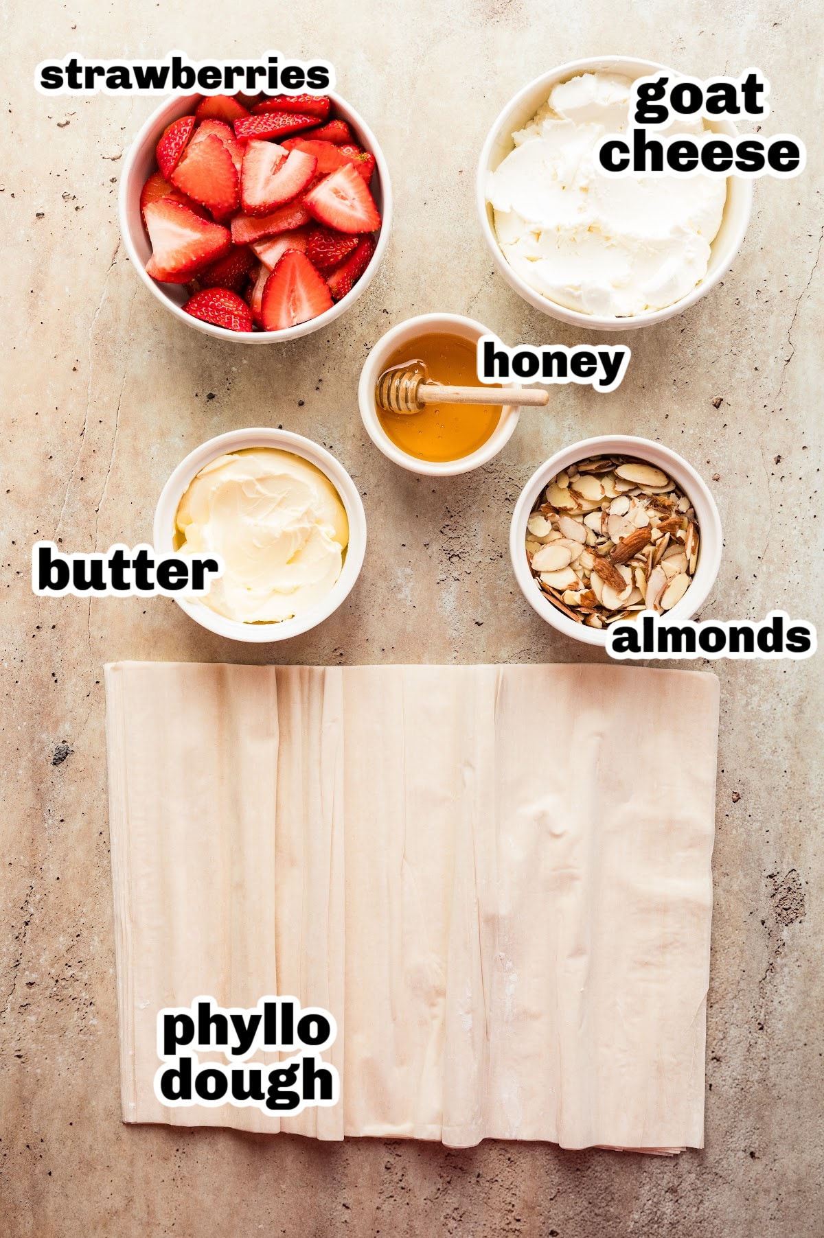 Strawberry Goat Cheese Tart (phyllo dough) ingredients All ingredients laid out for making the strawberry goat cheese tart, including phyllo dough, goat cheese, strawberries, honey, almonds, and butter.