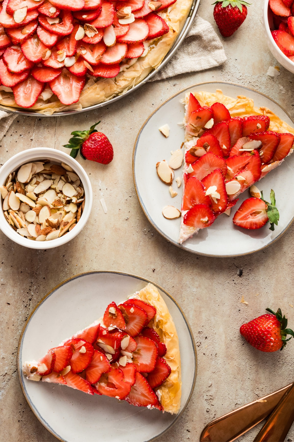 Strawberry Goat Cheese Tart (phyllo dough) on plates being served Overhead view of two slices of strawberry goat cheese tart served on plates, ready to eat.