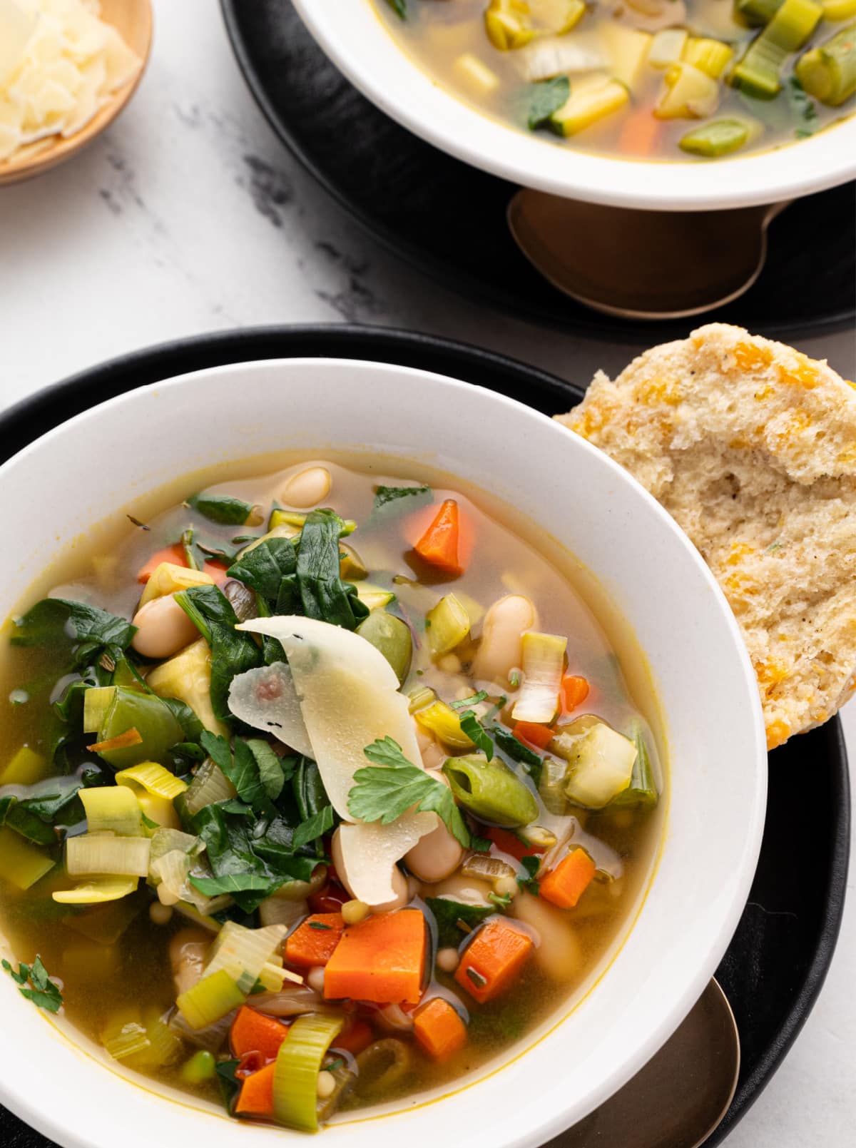 Top view of green minestrone with lemon and pasta pearls Overhead shot of two bowls of green minestrone with pasta pearls, lemon, and herbs