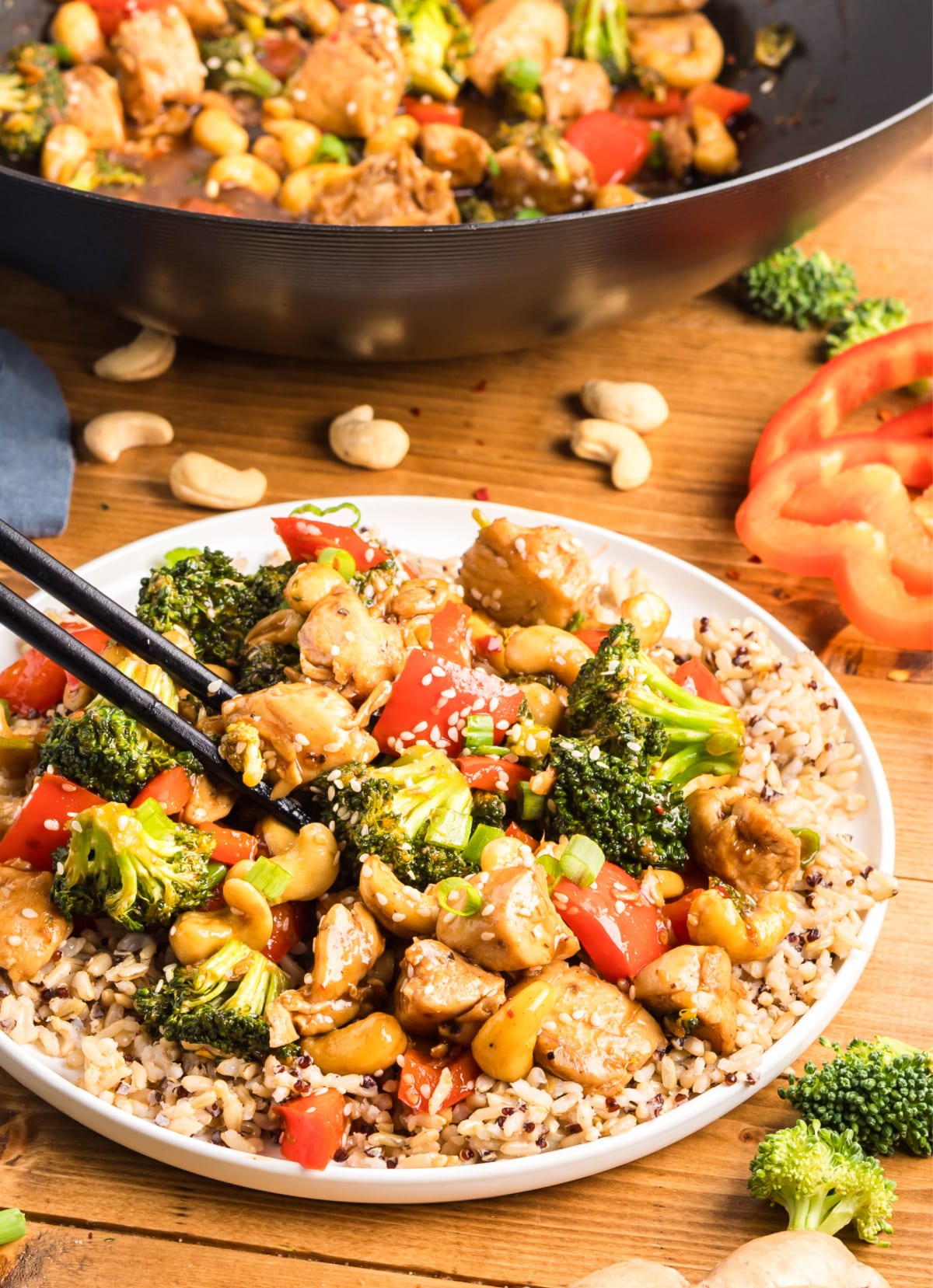 Chopsticks Picking Up Cashew Chicken Stir-Fry Side view of chopsticks lifting a bite of cashew chicken stir-fry from a plate