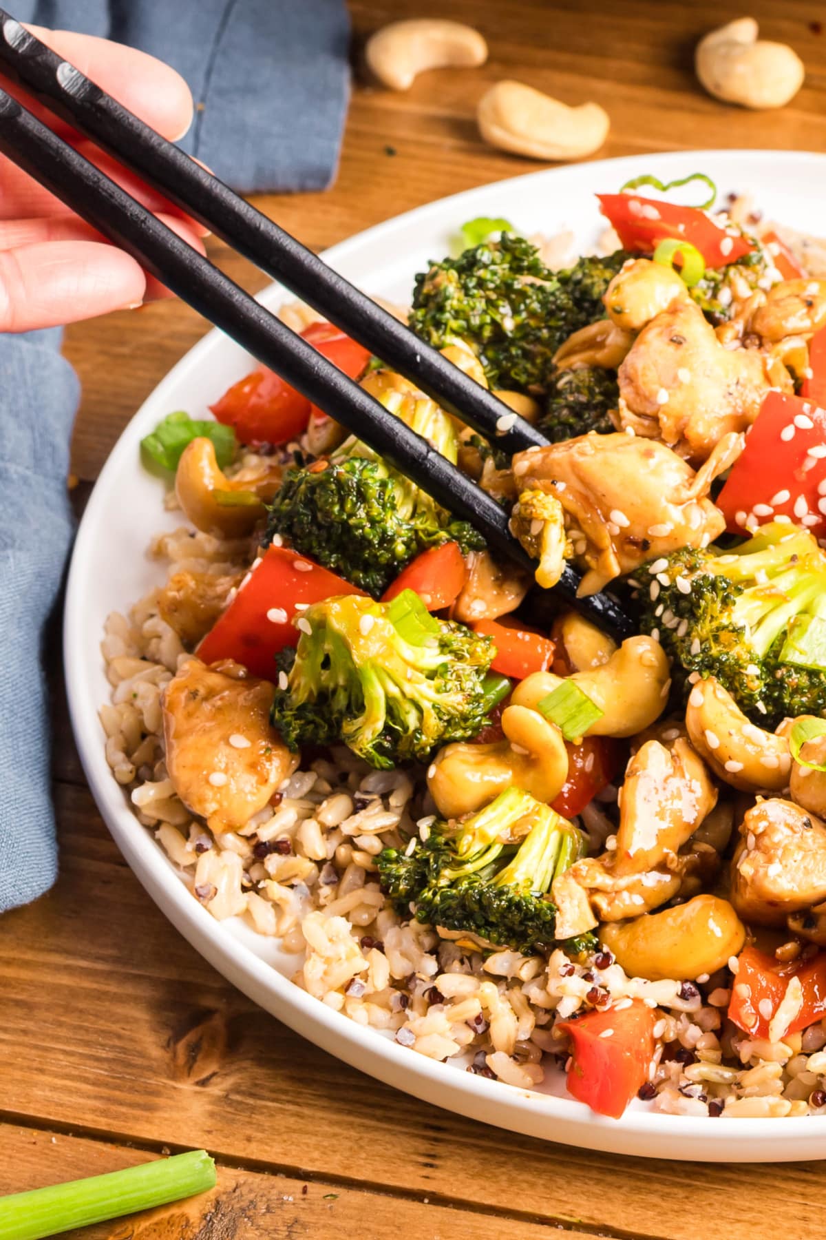 Close-Up of Cashew Chicken Stir-Fry with Chopsticks Close-up of chopsticks holding sticky cashew chicken with vegetables and cashews