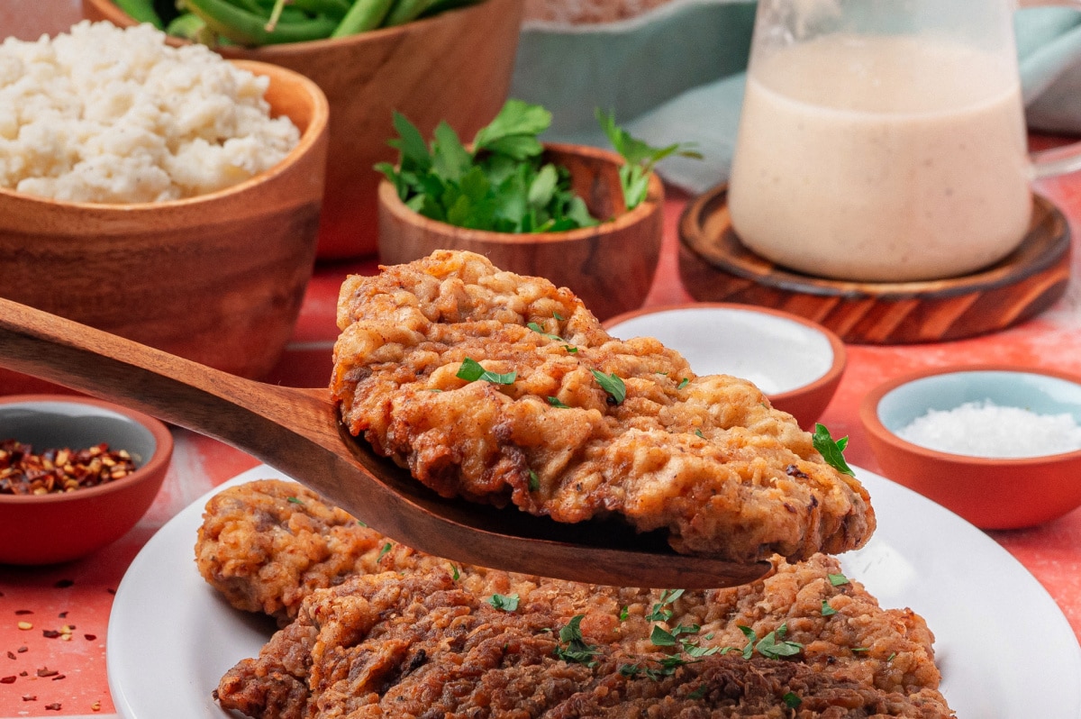 Side view of crispy chicken fried steak lifted with a spatula before adding gravy