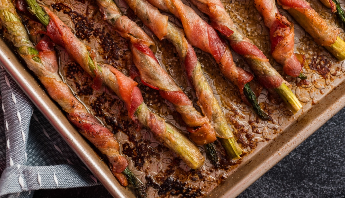 Crispy bacon-wrapped asparagus straight out of the oven Overhead view of bacon-wrapped asparagus freshly roasted on a baking sheet