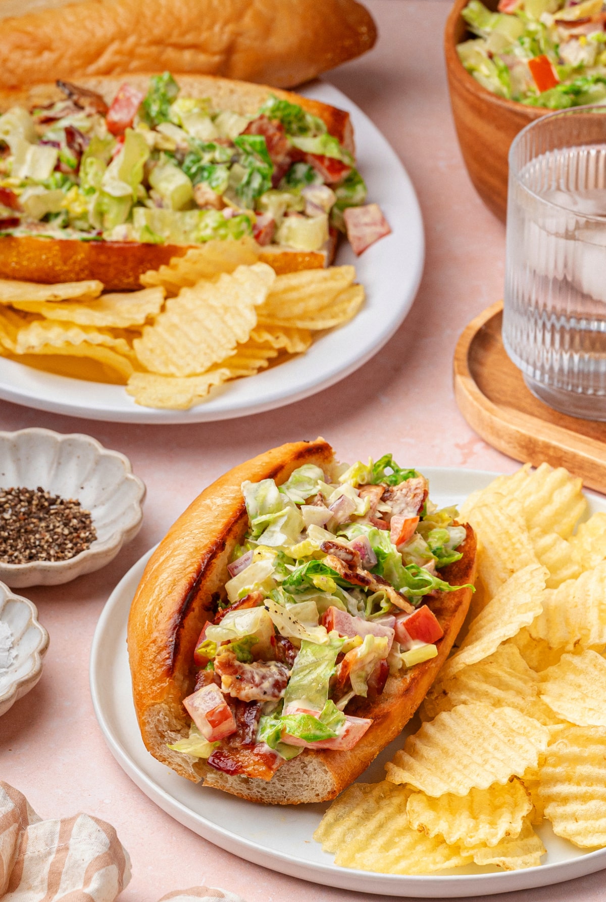 BLT hoagie sandwiches served with chips Chopped BLT hoagies served on plates with thick-cut potato chips on the side