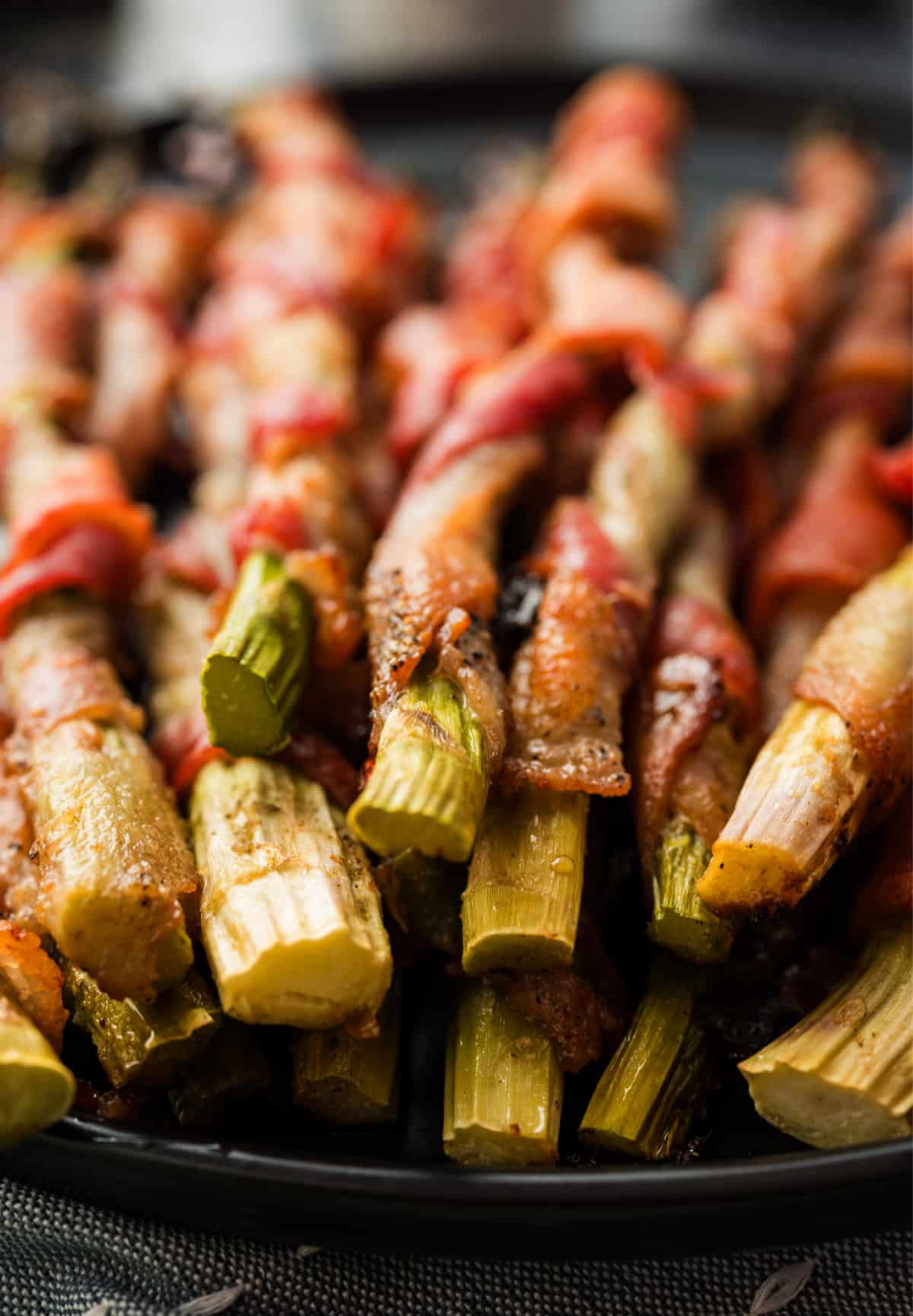Close view of crispy ends of bacon-wrapped asparagus on platter Bacon-wrapped asparagus on a serving platter with crisped ends visible