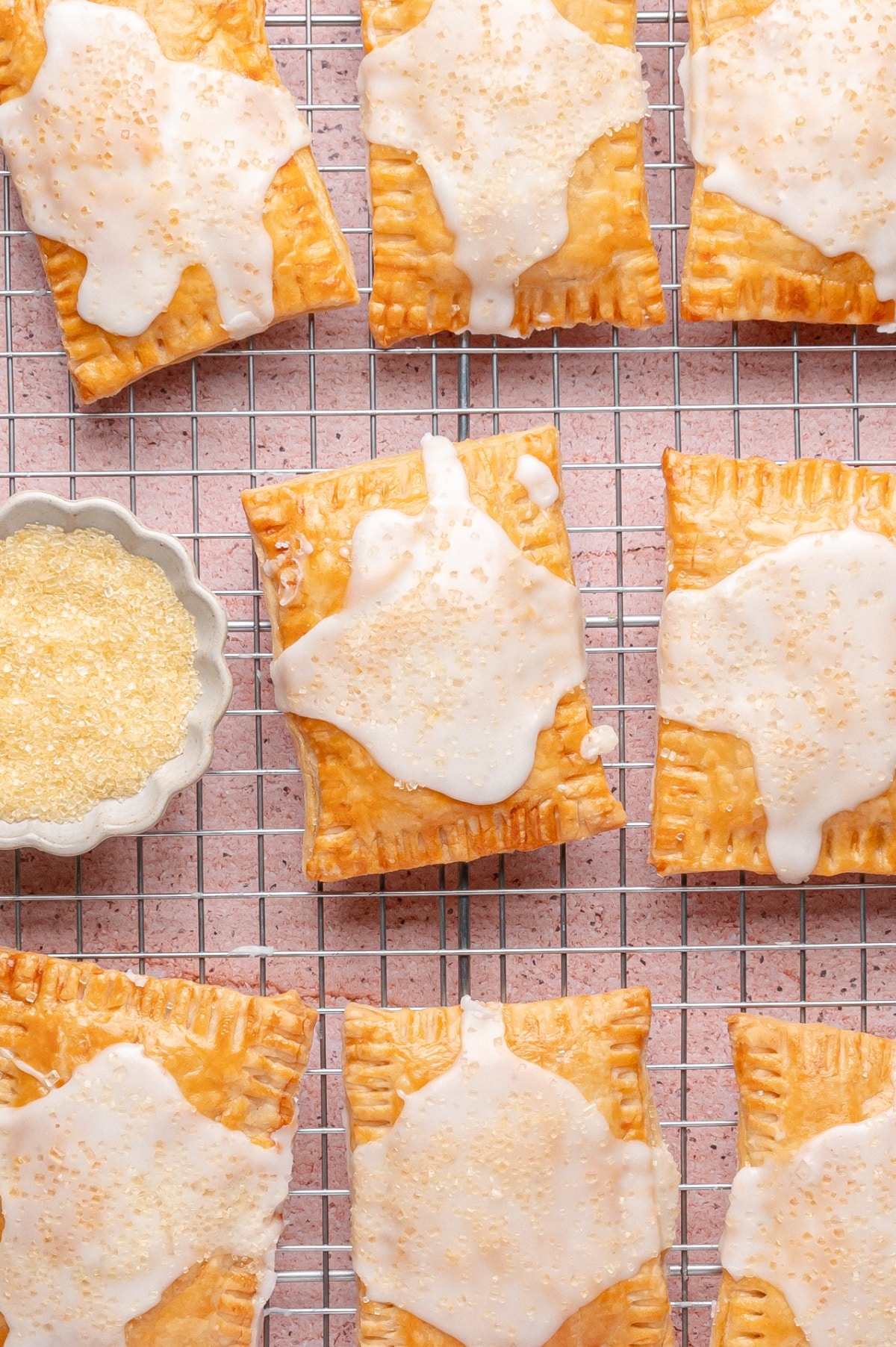 Glazed lemon pop tarts cooling on rack Homemade lemon pop tarts with glaze cooling on a wire rack, topped with coarse sugar sprinkles