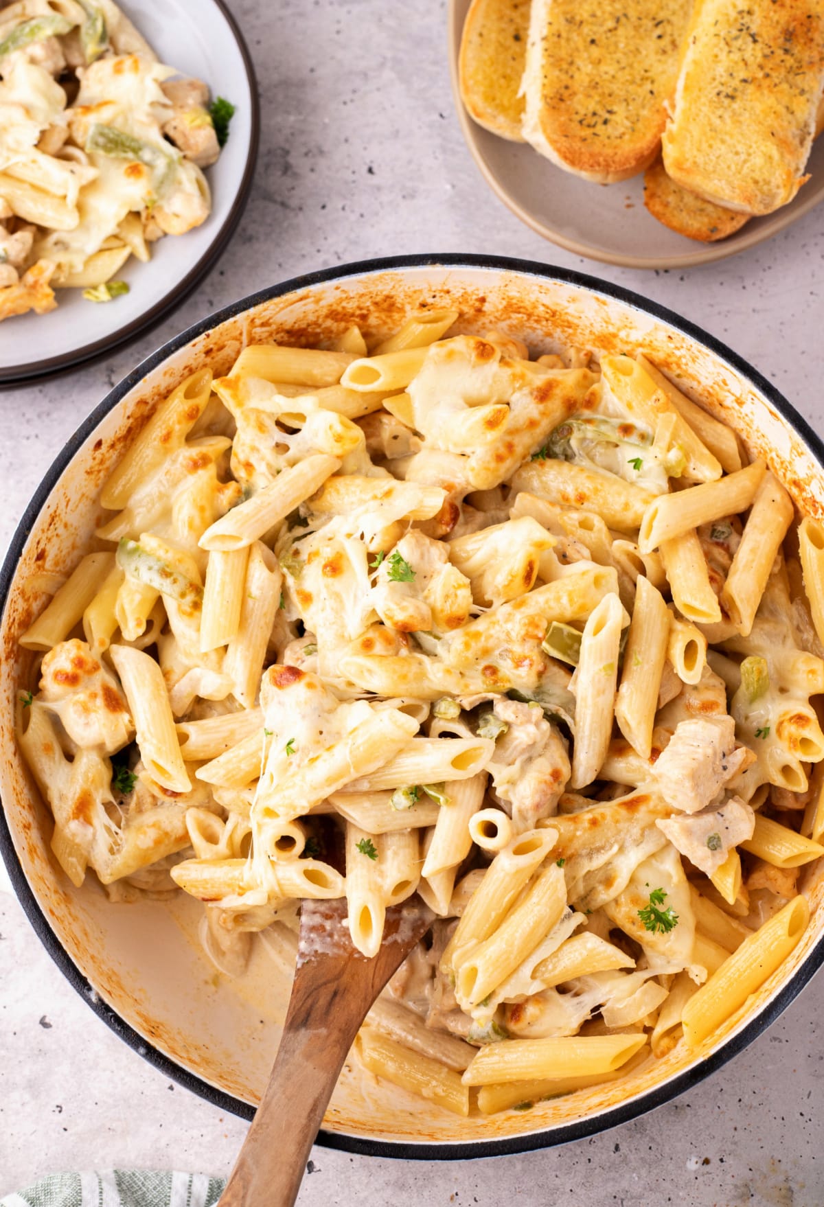 Serving of chicken Philly cheesesteak pasta on a plate with toasted garlic bread Plated serving of chicken Philly cheesesteak pasta with garlic bread and creamy sauce