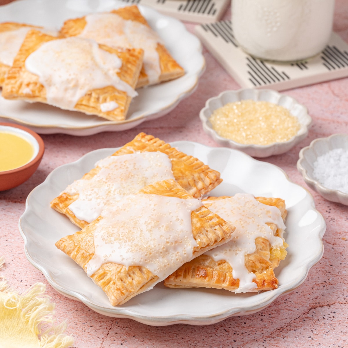 Easy lemon pop tarts plated for breakfast Plates of lemon toaster pastries served with milk and glaze, surrounded by ingredients