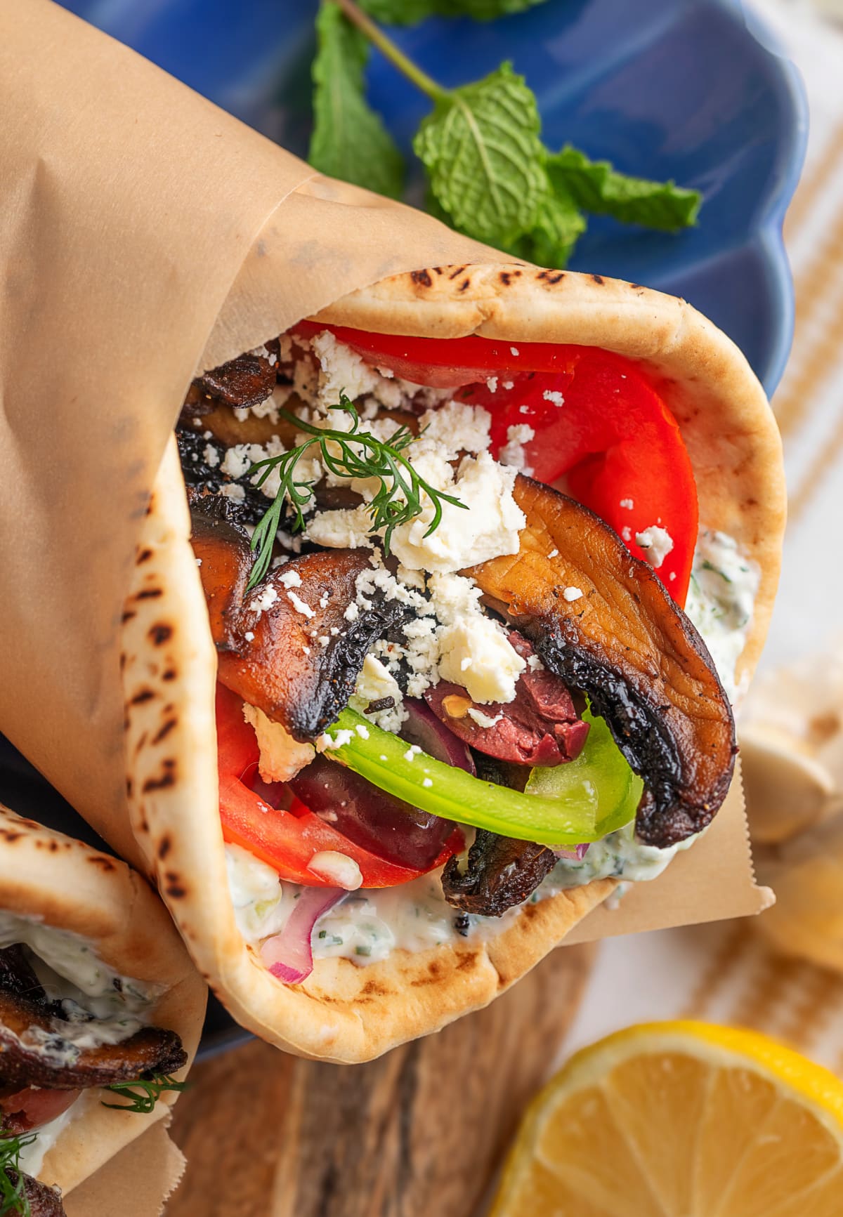 Close-up of one gyro wrapped in parchment with fillings visible.