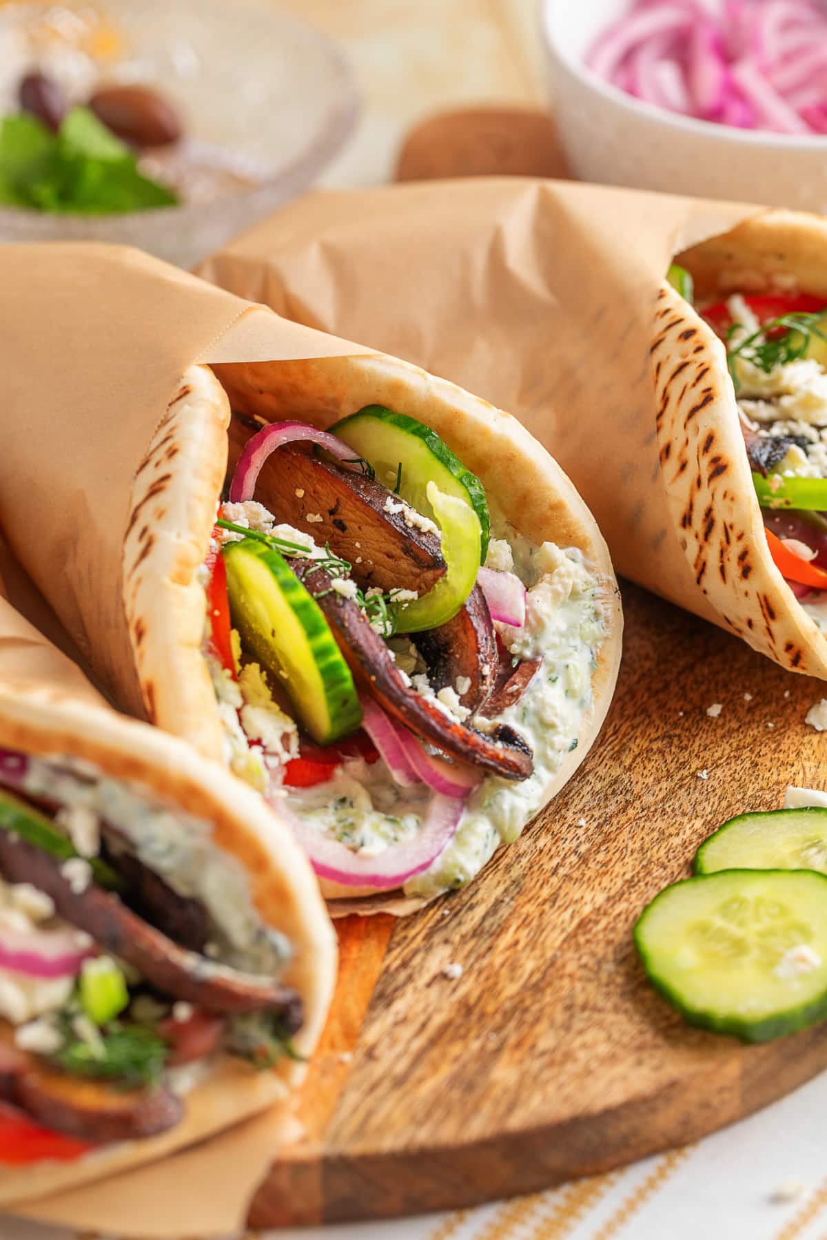 Three assembled portobello mushroom gyros wrapped in parchment, ready to serve. 