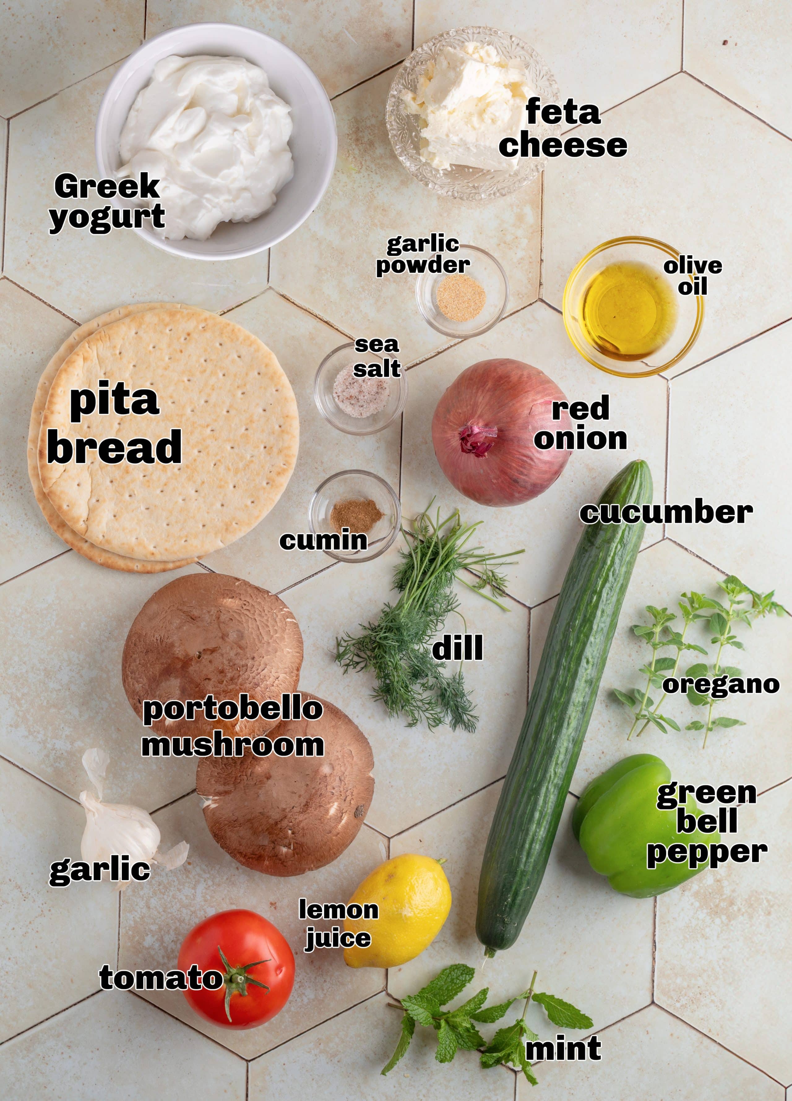 Ingredients for portobello mushroom gyros laid out on a white surface.