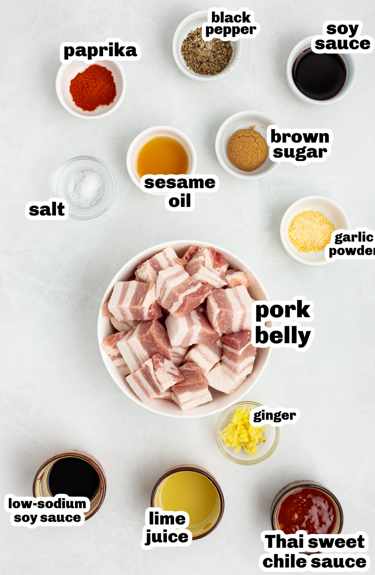 Flat lay of pork belly bite ingredients including brown sugar, soy sauce, sesame oil, garlic powder, paprika, and sweet chili sauce.