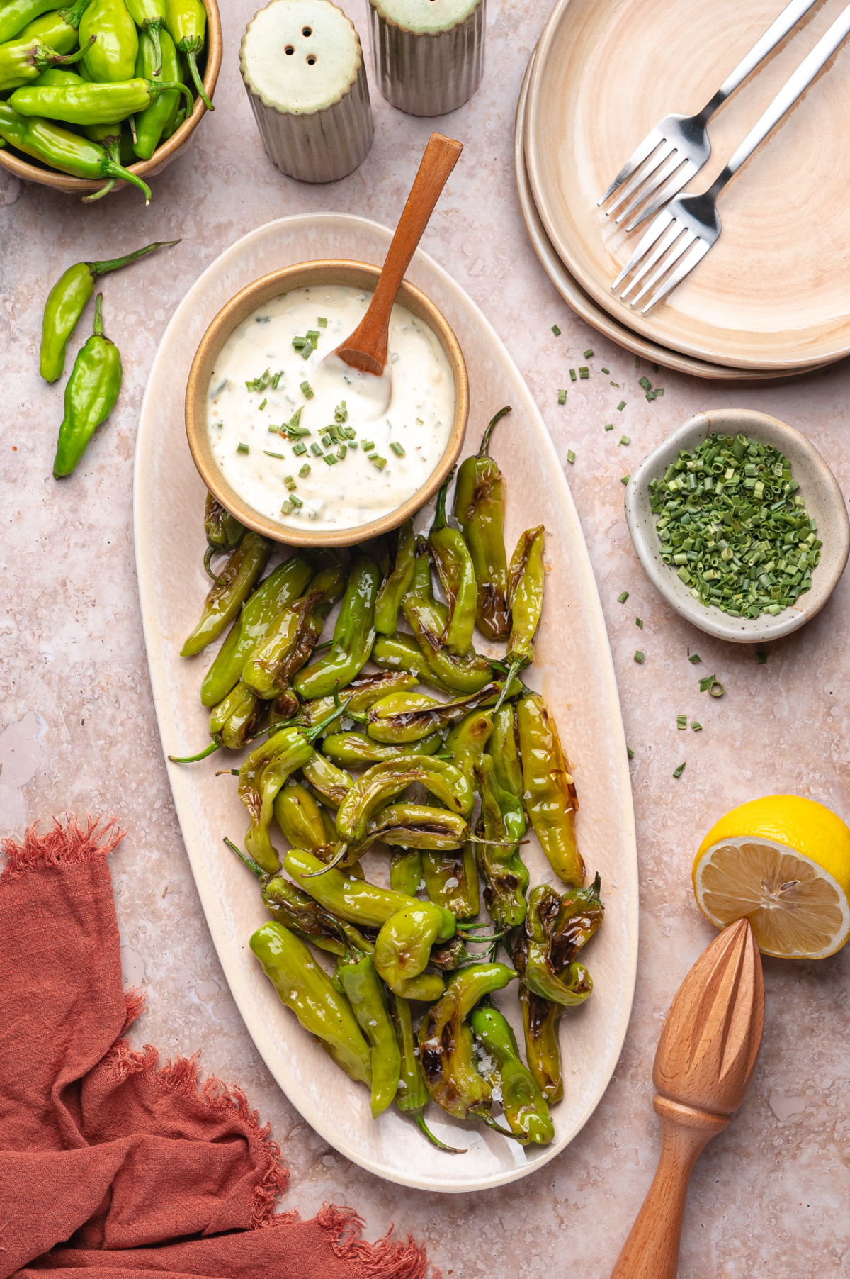 Large platter of blistered shishito peppers served with garlic chive aioli, lemon, and dried chives