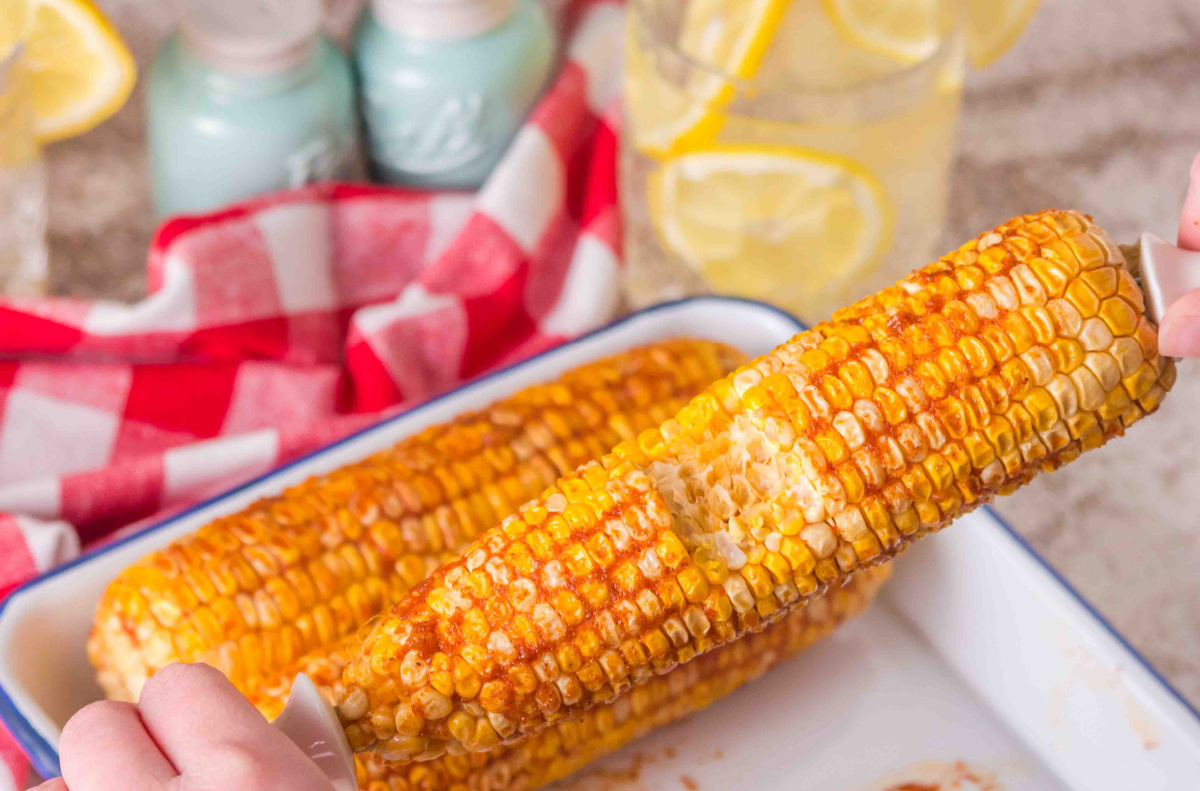 Smoked corn on the cob with bite taken, served with garlic butter and paprika