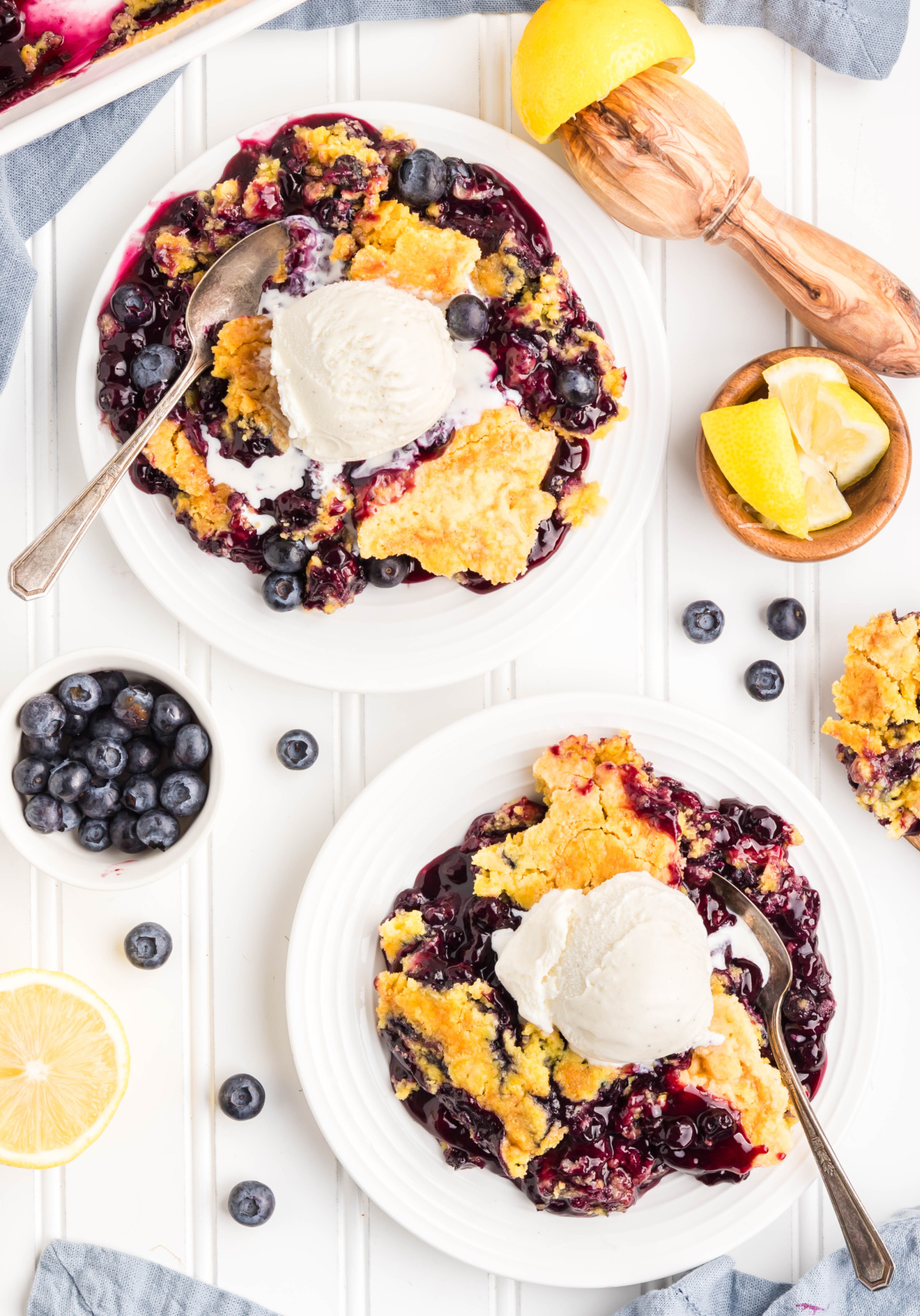 Lemon blueberry dessert served with ice cream. Two plates of lemon blueberry dessert with scoops of ice cream.