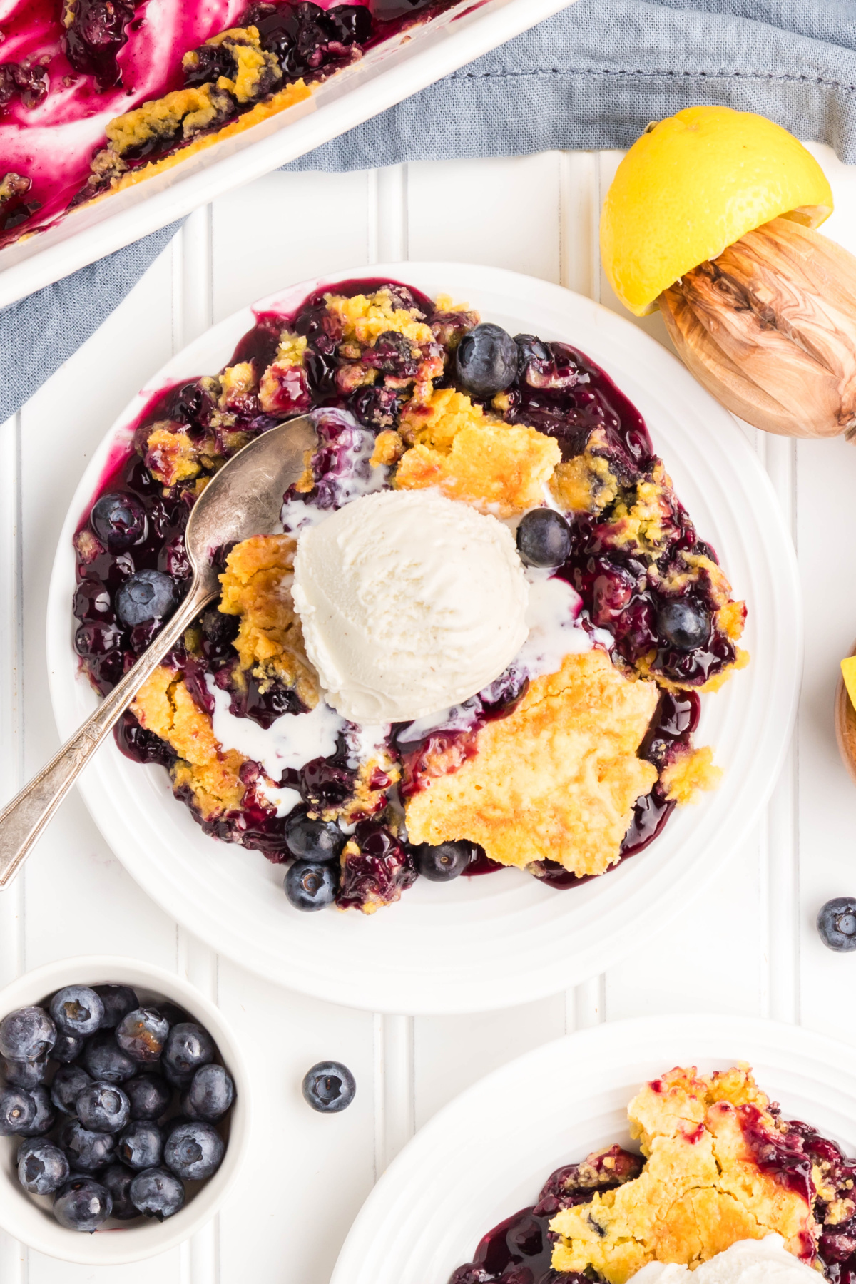 Blueberry dump cake with pie filling and fresh berries. Overhead view of blueberry dump cake served with vanilla ice cream and fresh blueberries.