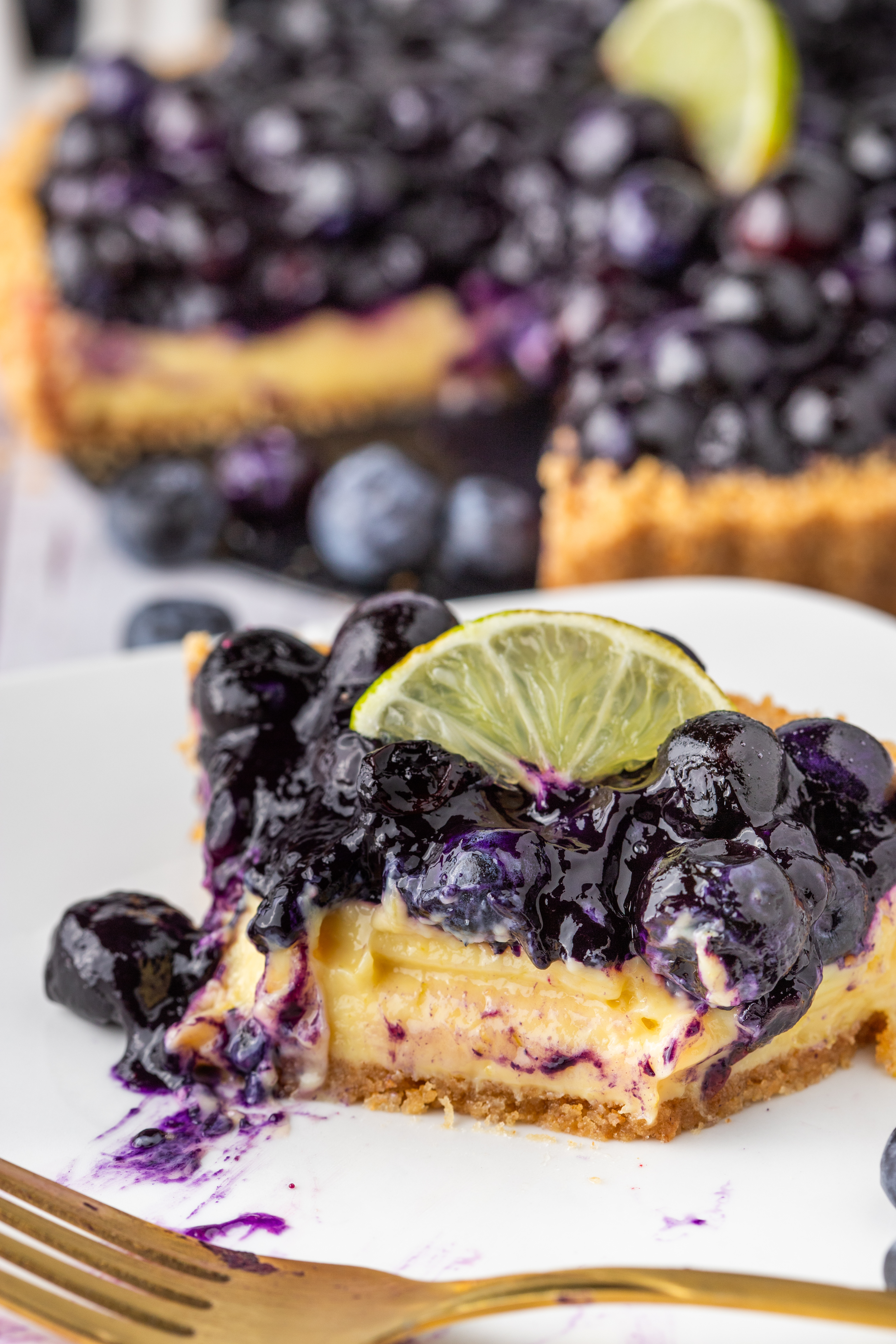 Blueberry Lime Tart slice topped with blueberries and lime.