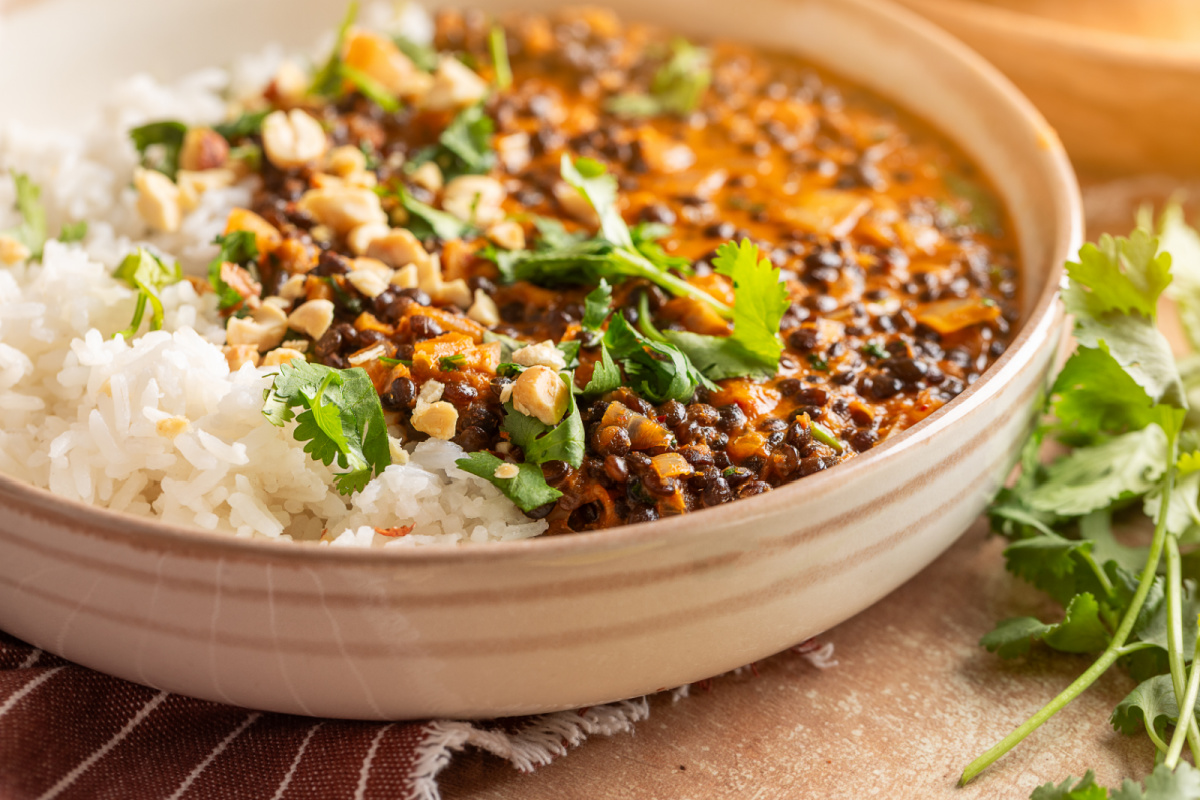 Side view of Marry Me Lentils with creamy coconut curry and black lentils served over rice.