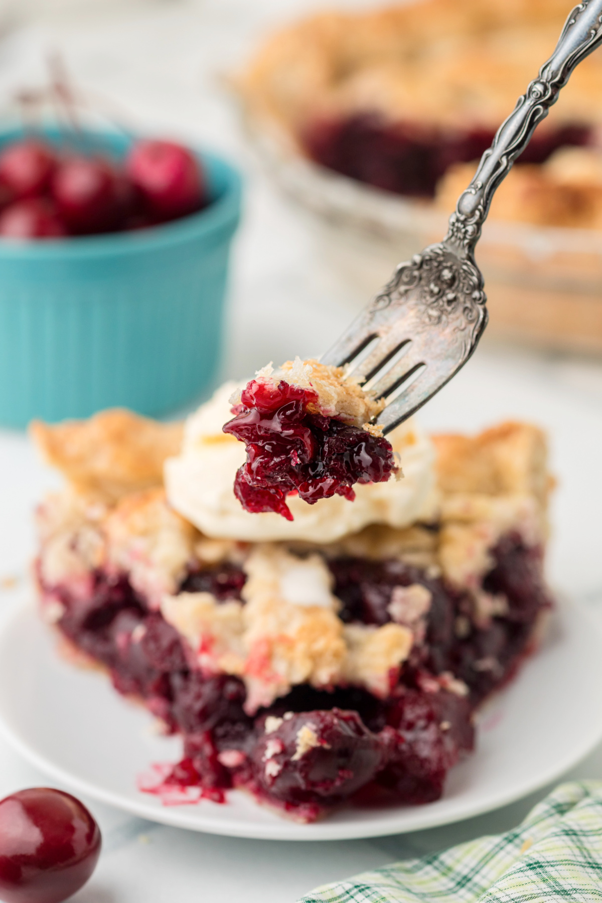 Forkful of Fresh Cherry Pie showing thick cherry filling with a slice in the background