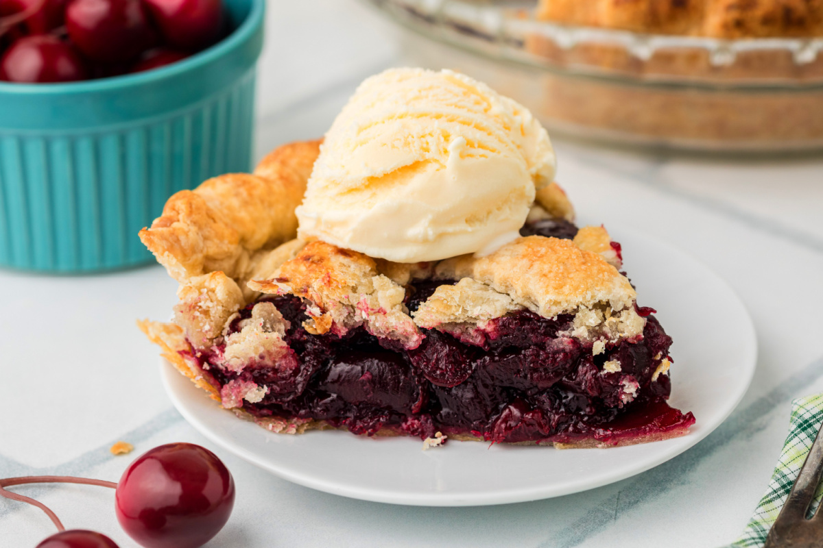 Fresh Cherry Pie slice topped with vanilla ice cream showing thick cherry filling and flaky homemade crust