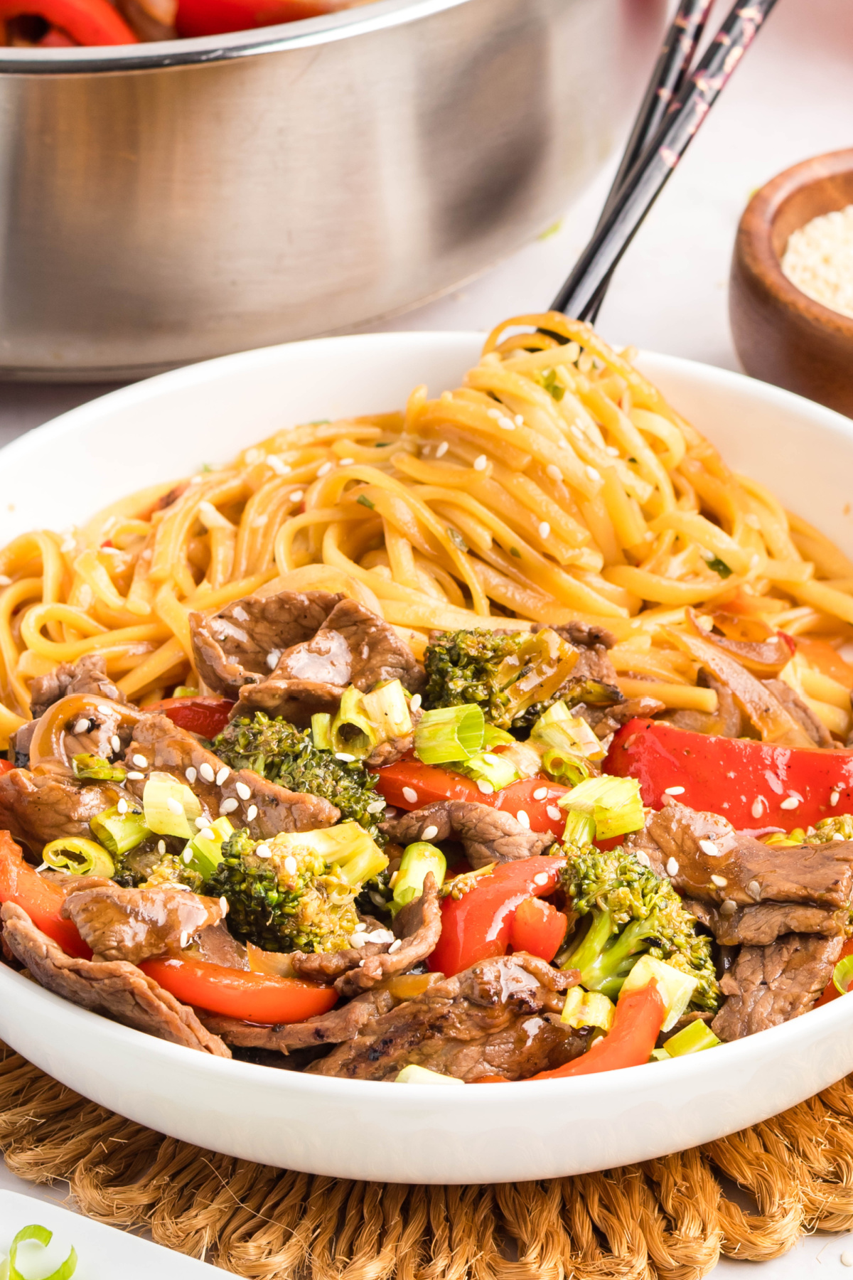 Noodles with teriyaki beef, broccoli, and peppers topped with sesame seeds