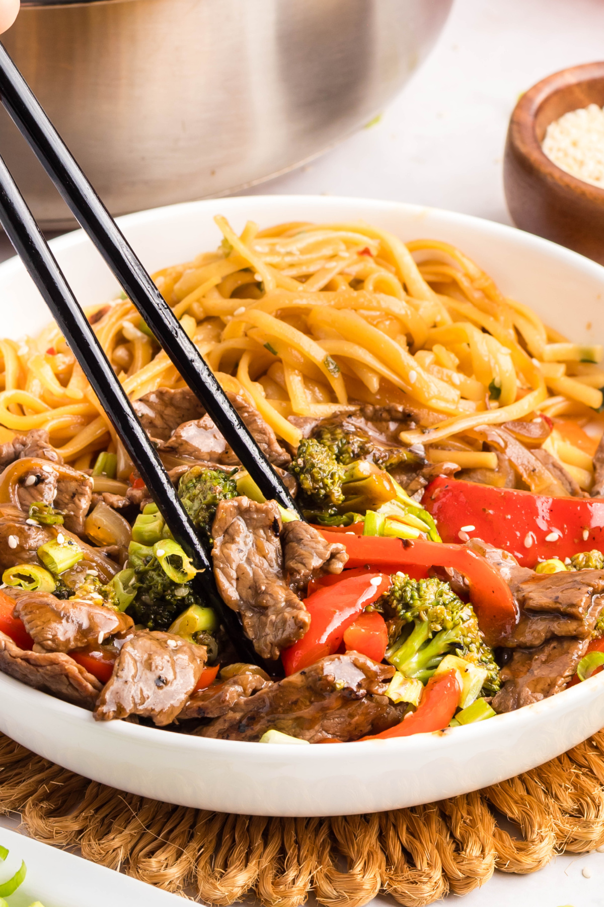 Chopsticks lifting beef and broccoli from teriyaki stir fry