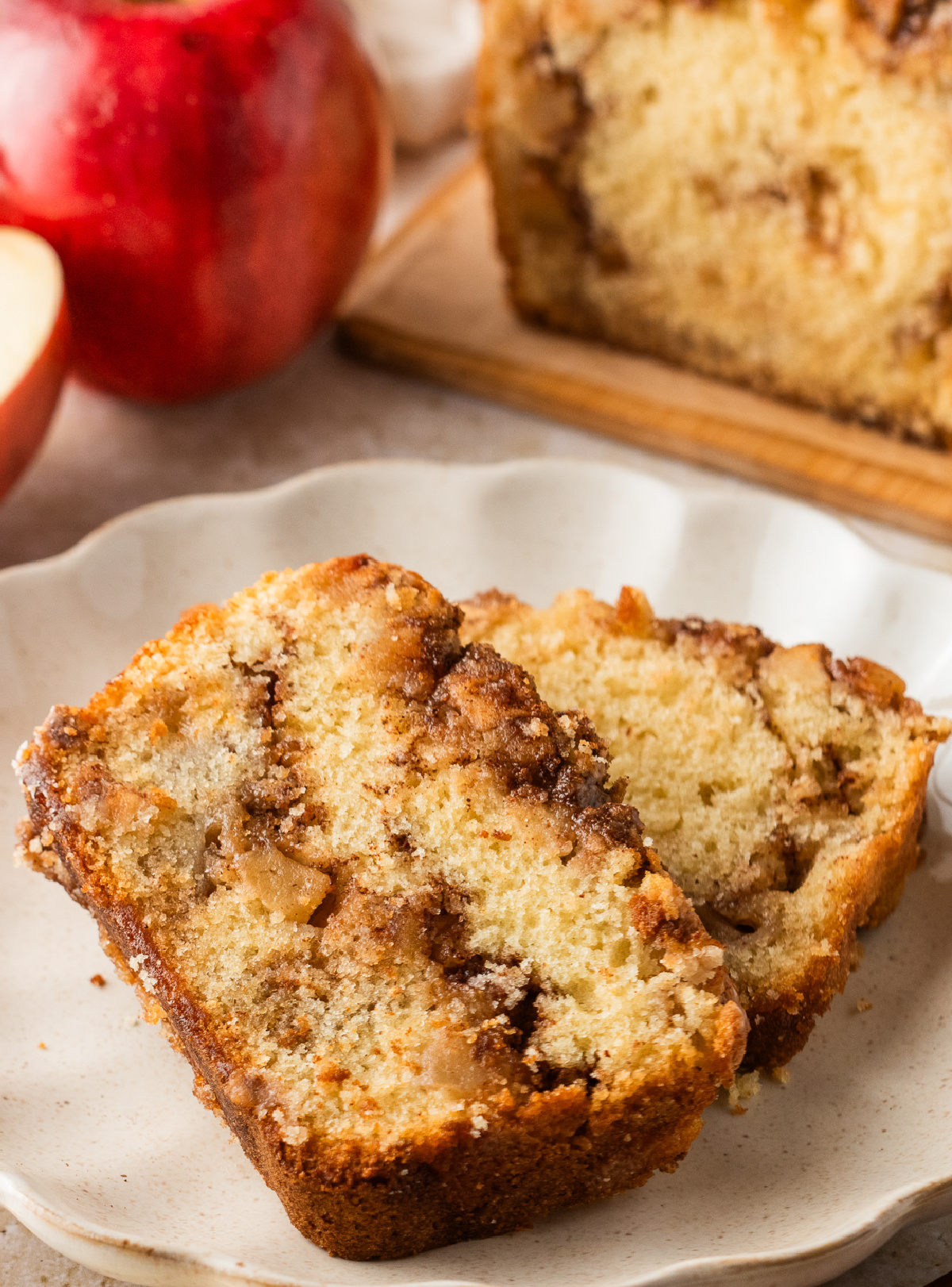 Slices of apple fritter loaf on a plate with visible chunks of apples and swirl.