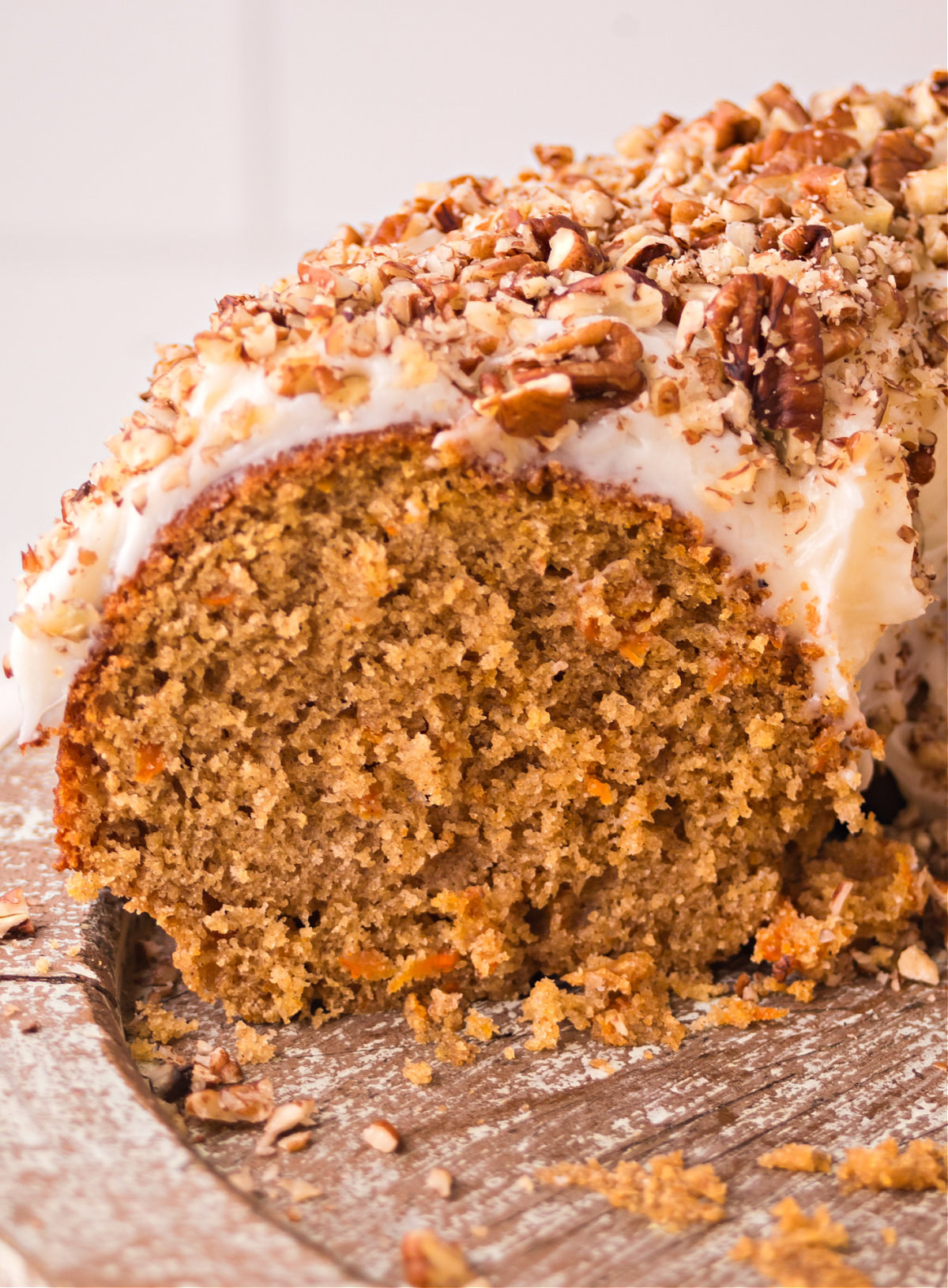 brown butter carrot bundt cake slice Close-up of brown butter carrot bundt cake slice topped with cream cheese frosting and walnuts.