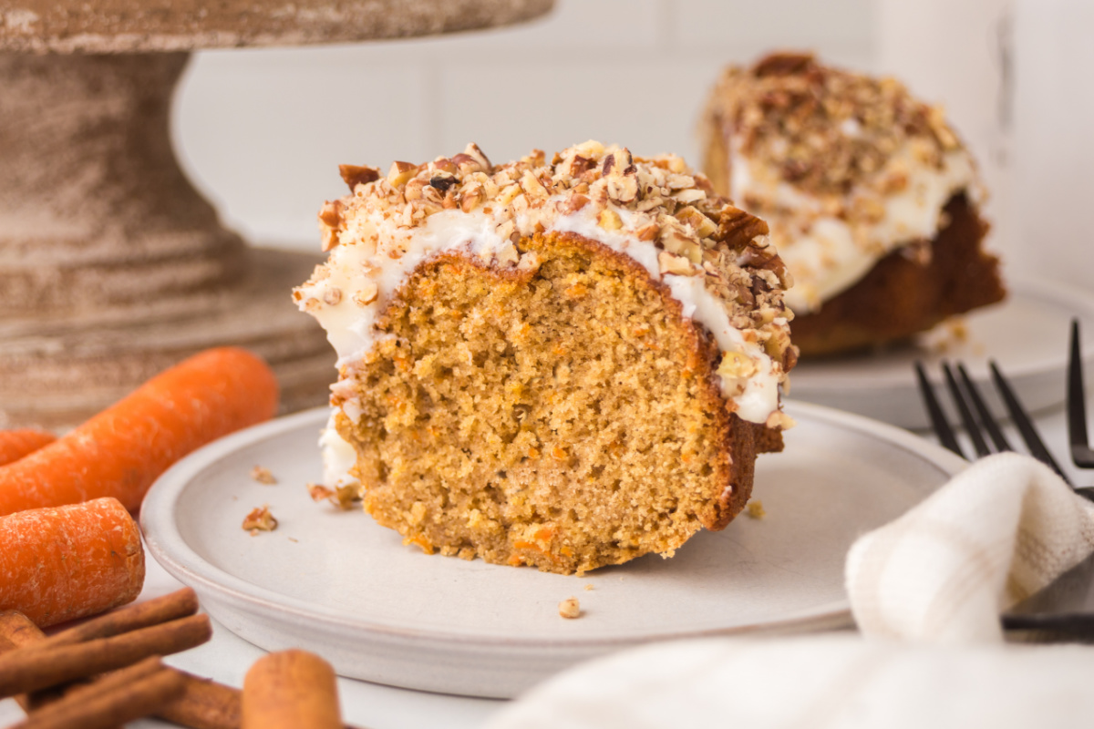 fall carrot bundt cake slice Fall carrot bundt cake slice on a plate with cream cheese frosting and walnuts.