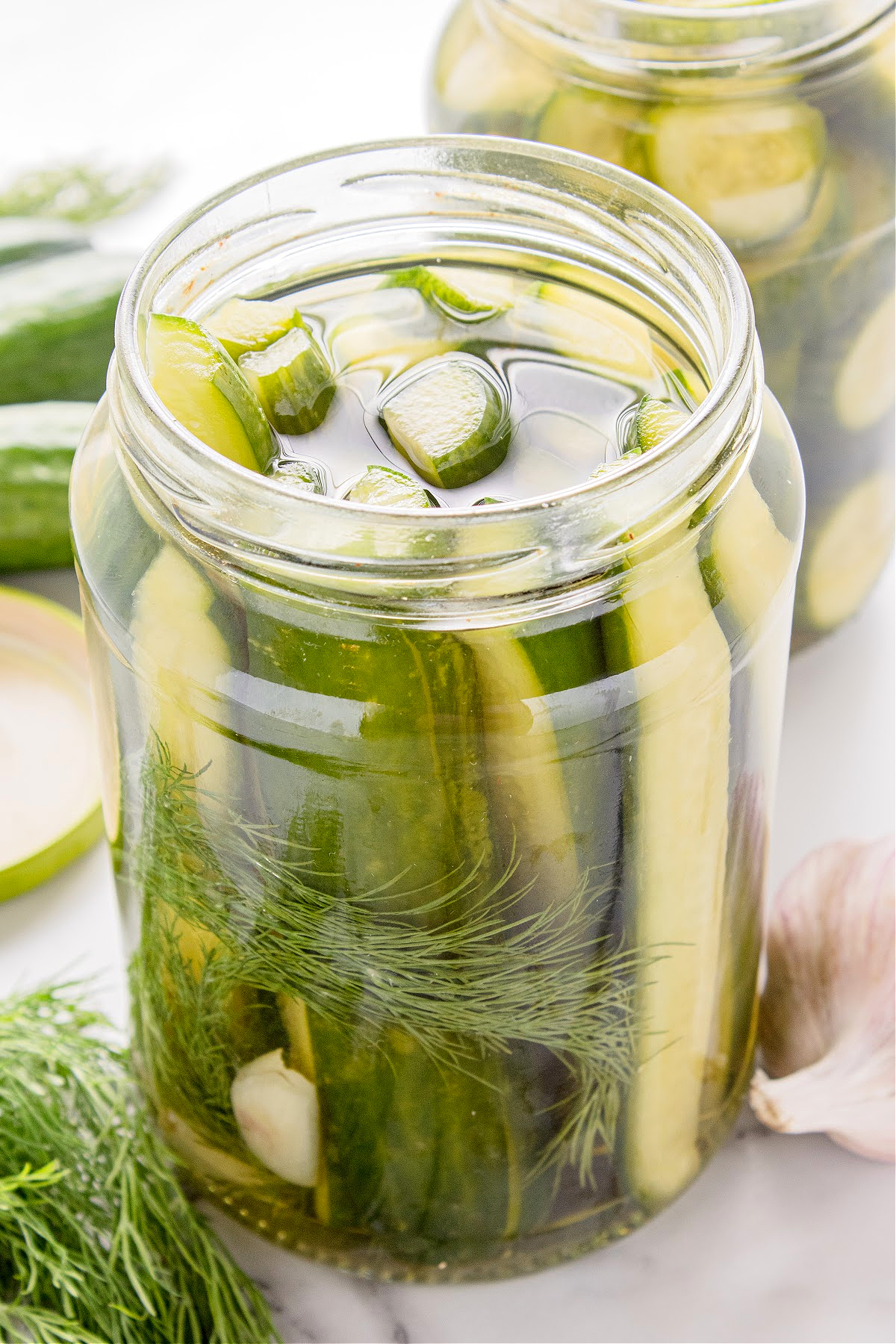 Jar of homemade dill pickles with cucumber spears, garlic, and fresh dill in brine.