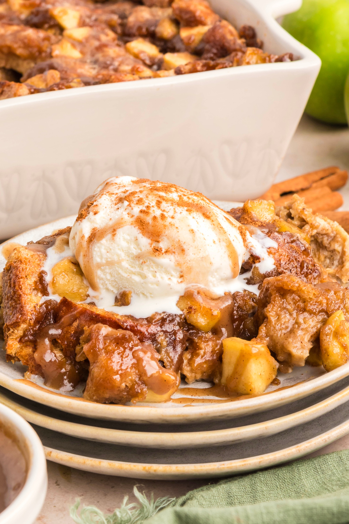 Custardy brioche bread pudding with caramel and vanilla ice cream. Close-up of custardy brioche bread pudding with caramel sauce and soft baked apples topped with melting vanilla ice cream.