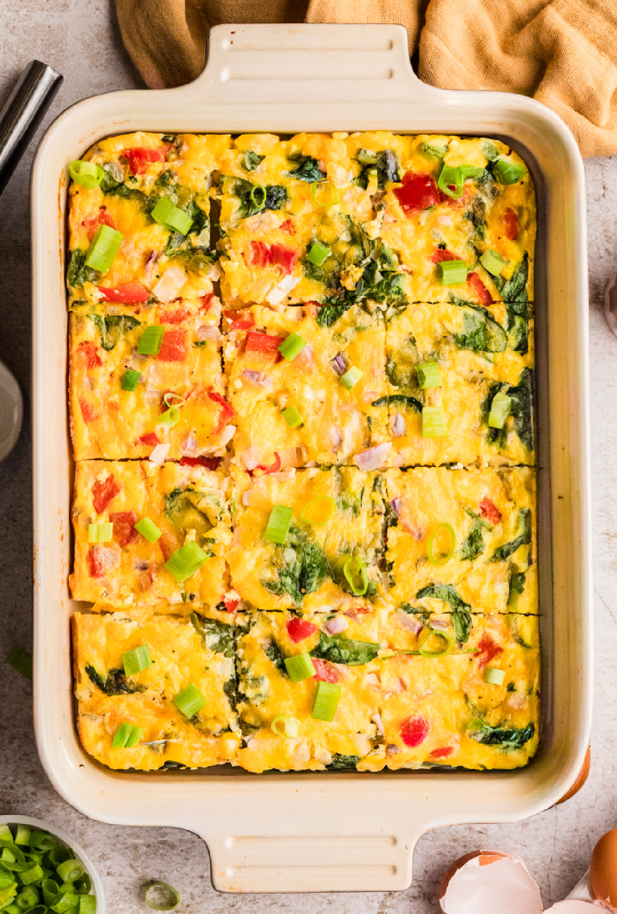 Cottage cheese egg bake baked in a dish with spinach, peppers, and cheddar cut into squares