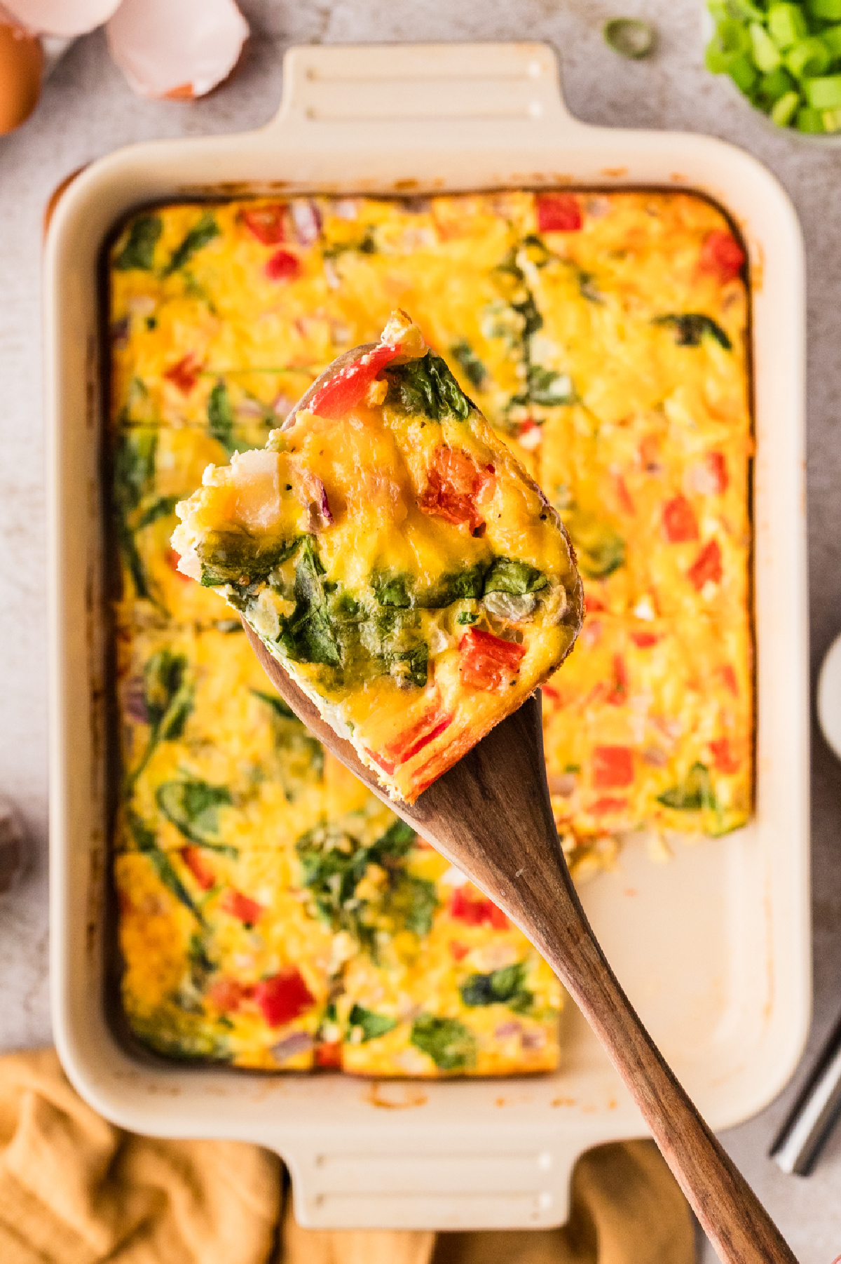 Egg bake with cottage cheese slice lifted from baking dish showing spinach and red pepper 