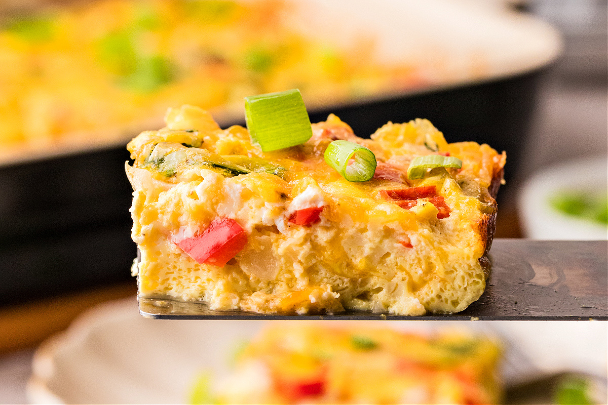Cottage cheese egg casserole square topped with green onions on spatula