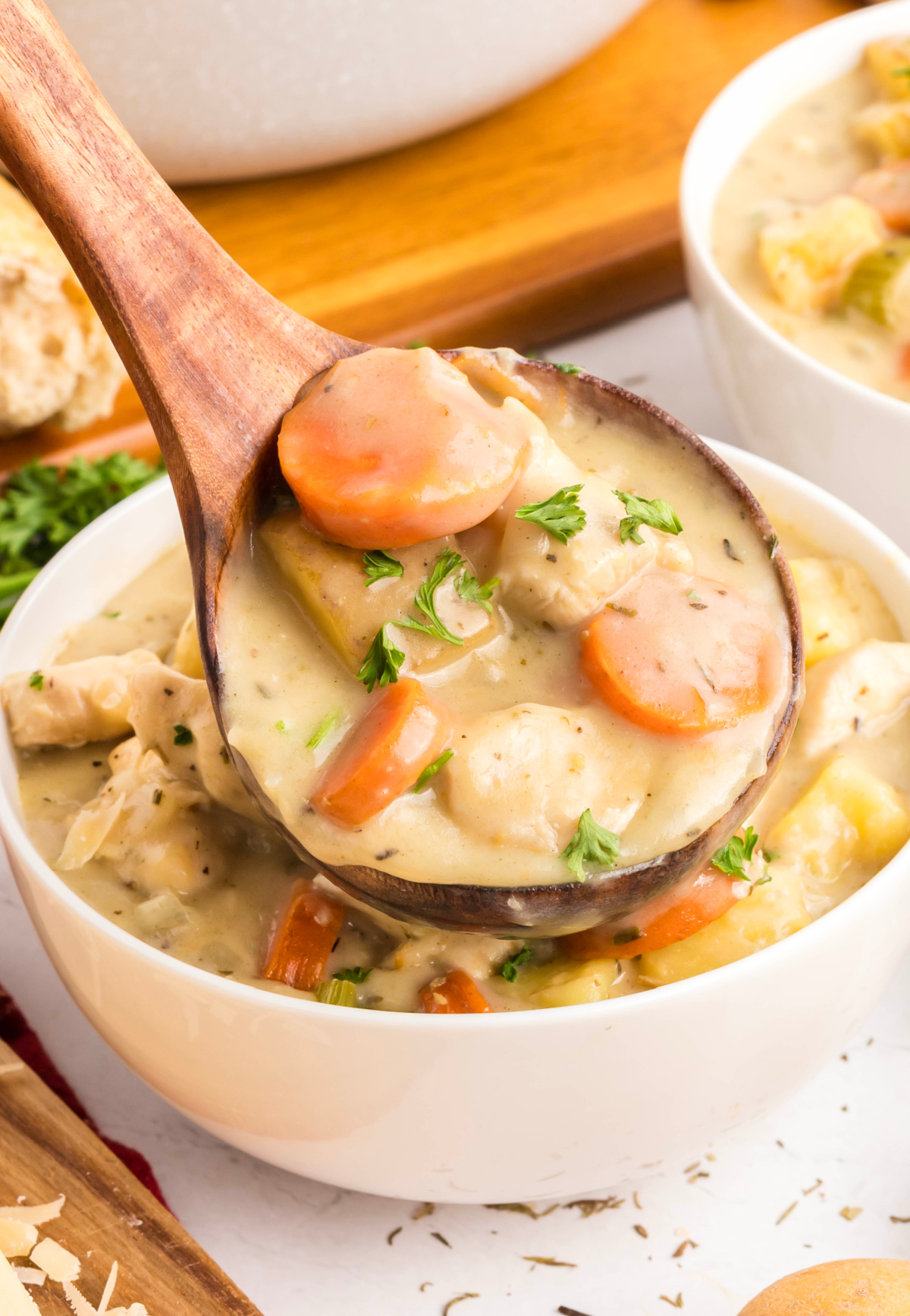 ladle of one-pot chicken stew with carrots, potatoes, and chunks of chicken in a thick creamy broth, topped with parsley.