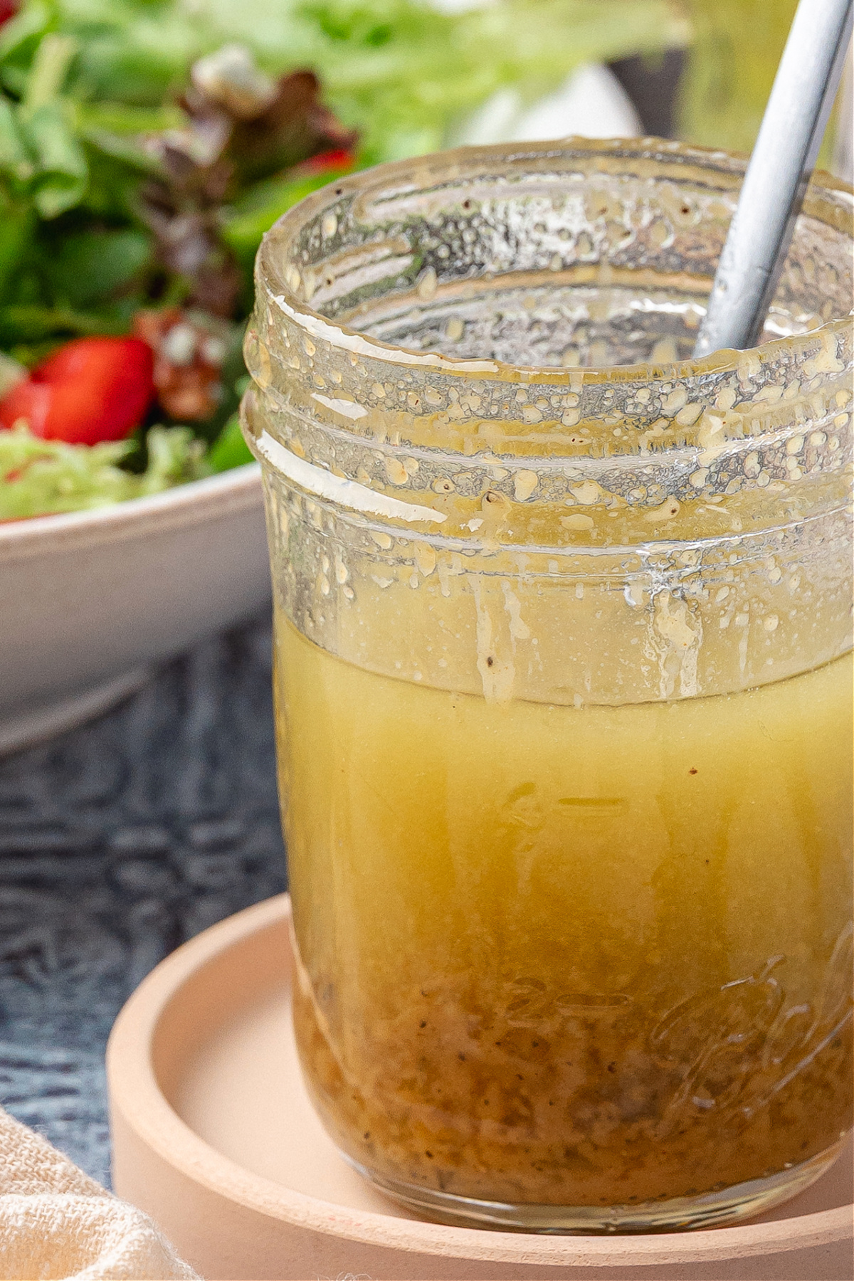 Honey champagne vinaigrette in a glass jar with visible mustard and pepper, ready to pour over salad greens.