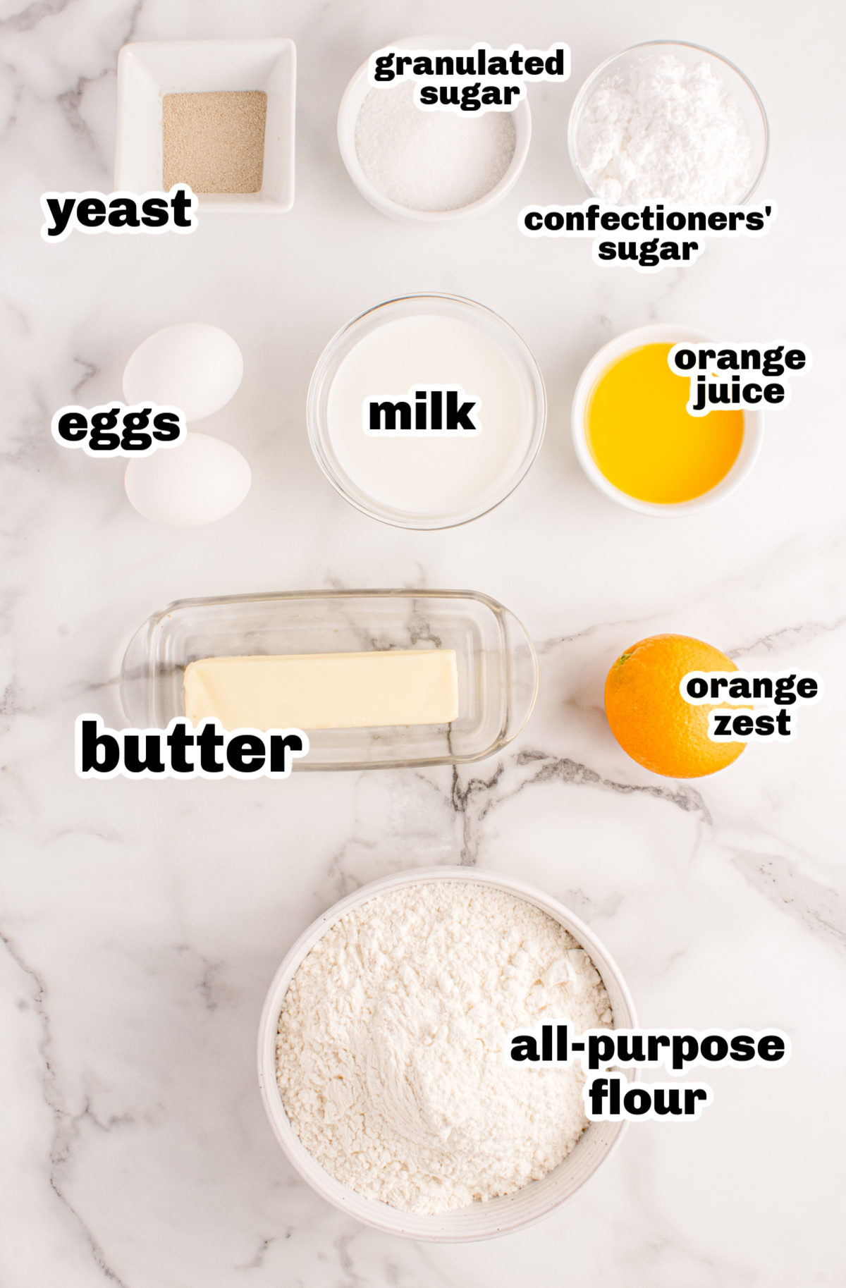 Ingredients for Orange Knot Rolls Overhead view of ingredients for orange rolls including flour, eggs, butter, milk, orange juice, and zest.