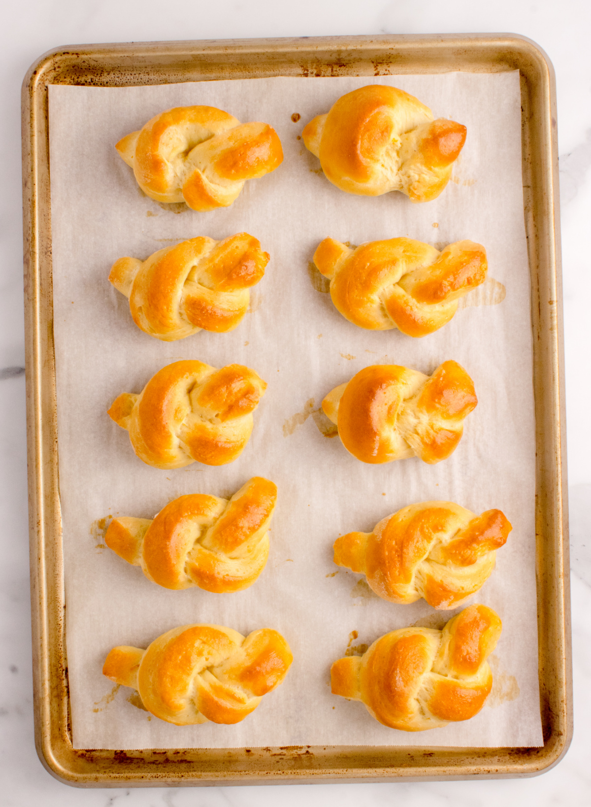 Orange Bread Knots Fresh from the Oven Freshly baked orange bread knots cooling on a parchment-lined baking sheet.