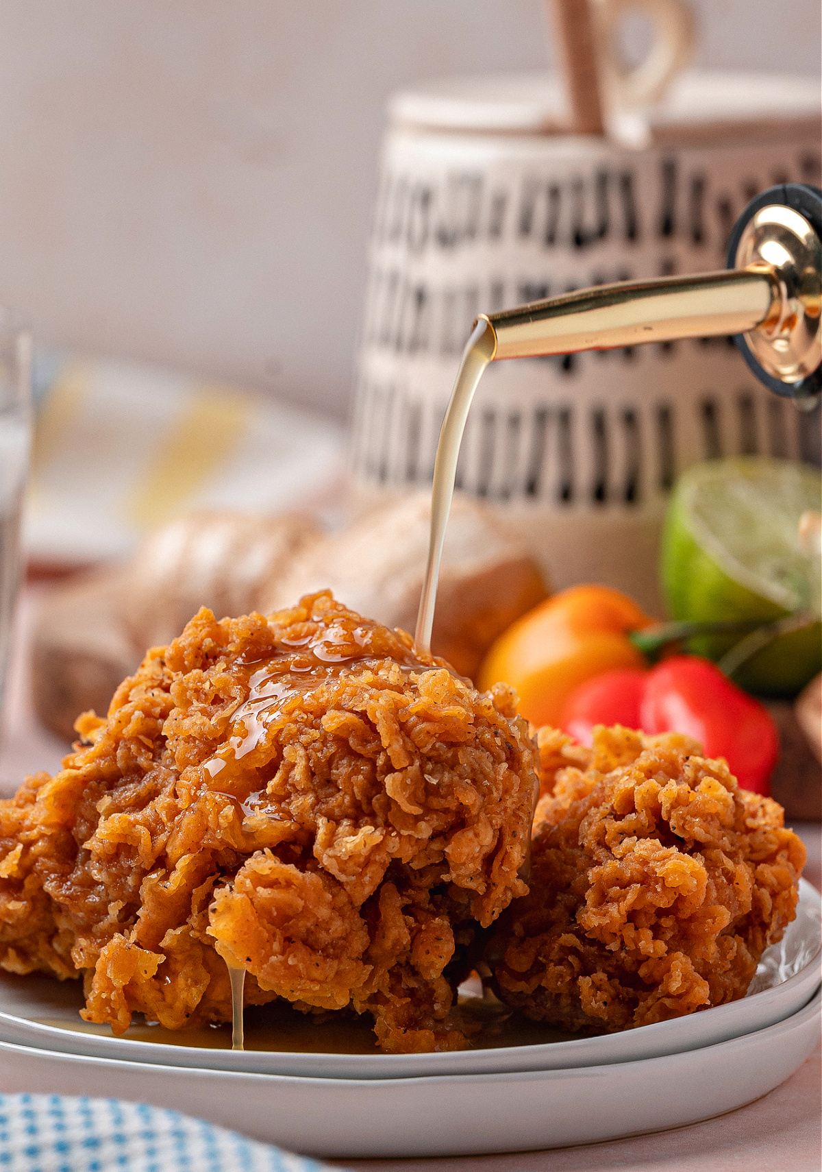 Golden fried chicken pieces with pineapple hot sauce being poured from a glass bottle. 