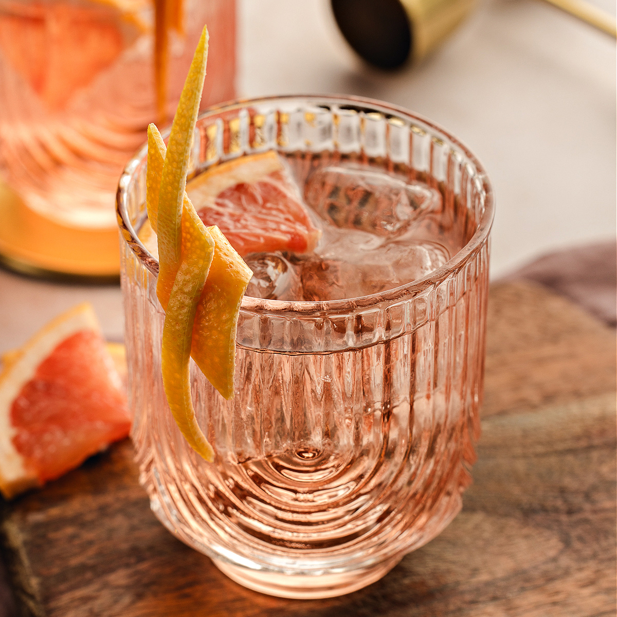 A close, square-cropped Lillet Rosé spritz served over ice in a textured glass with a long grapefruit twist resting on the rim.