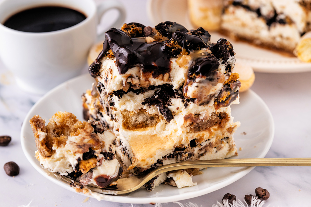 Slice of toffee tiramisu by Noble Pig with espresso-soaked ladyfingers, mascarpone toffee cream, chocolate drizzle, and crushed Toffee Crunch OREOs.