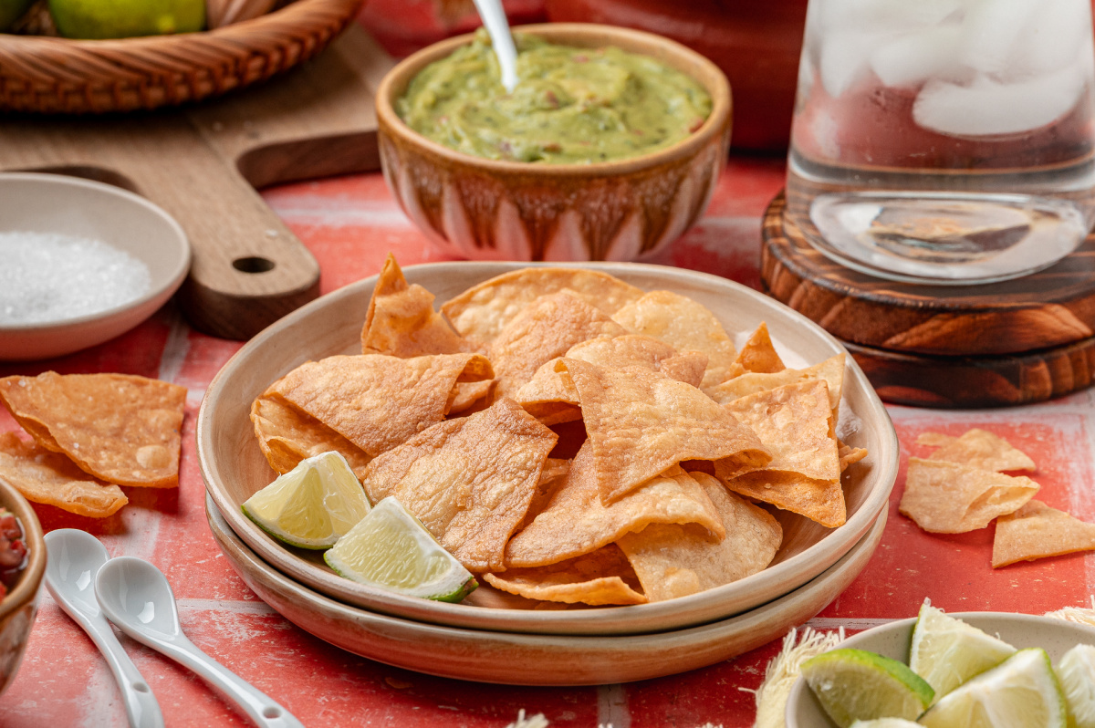 Crispy corn tortilla chips fried until golden A small plate of crispy tortilla chips with visible bubbles and light golden edges.
