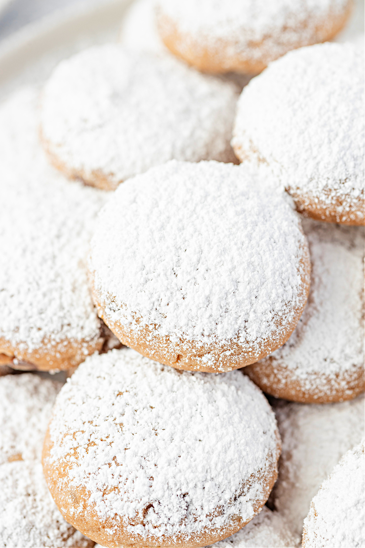 A close view of Danish wedding cookies covered in powdered sugar. Danish wedding cookies piled together and dusted generously with confectioners’ sugar.