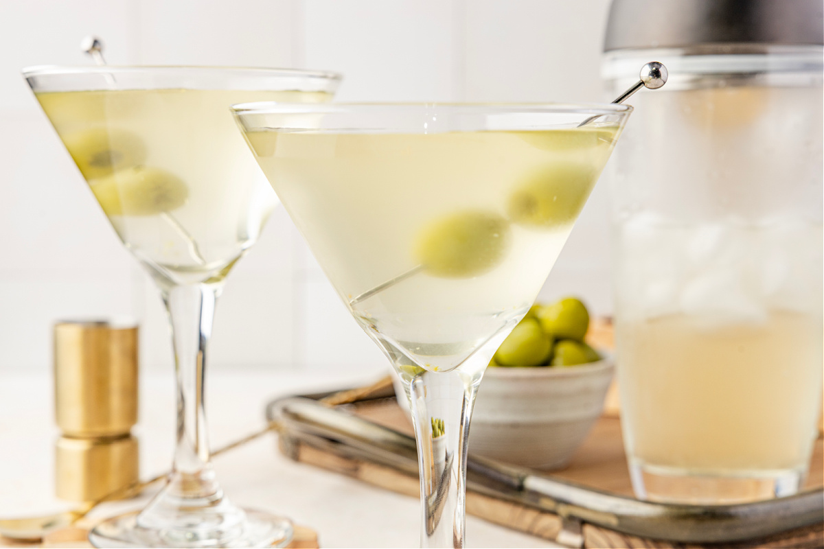 Brine-heavy dirty martini with green olives served ice-cold in a classic martini glass. A very dirty martini resting in a chilled glass with green olives suspended in the pale, briny cocktail.