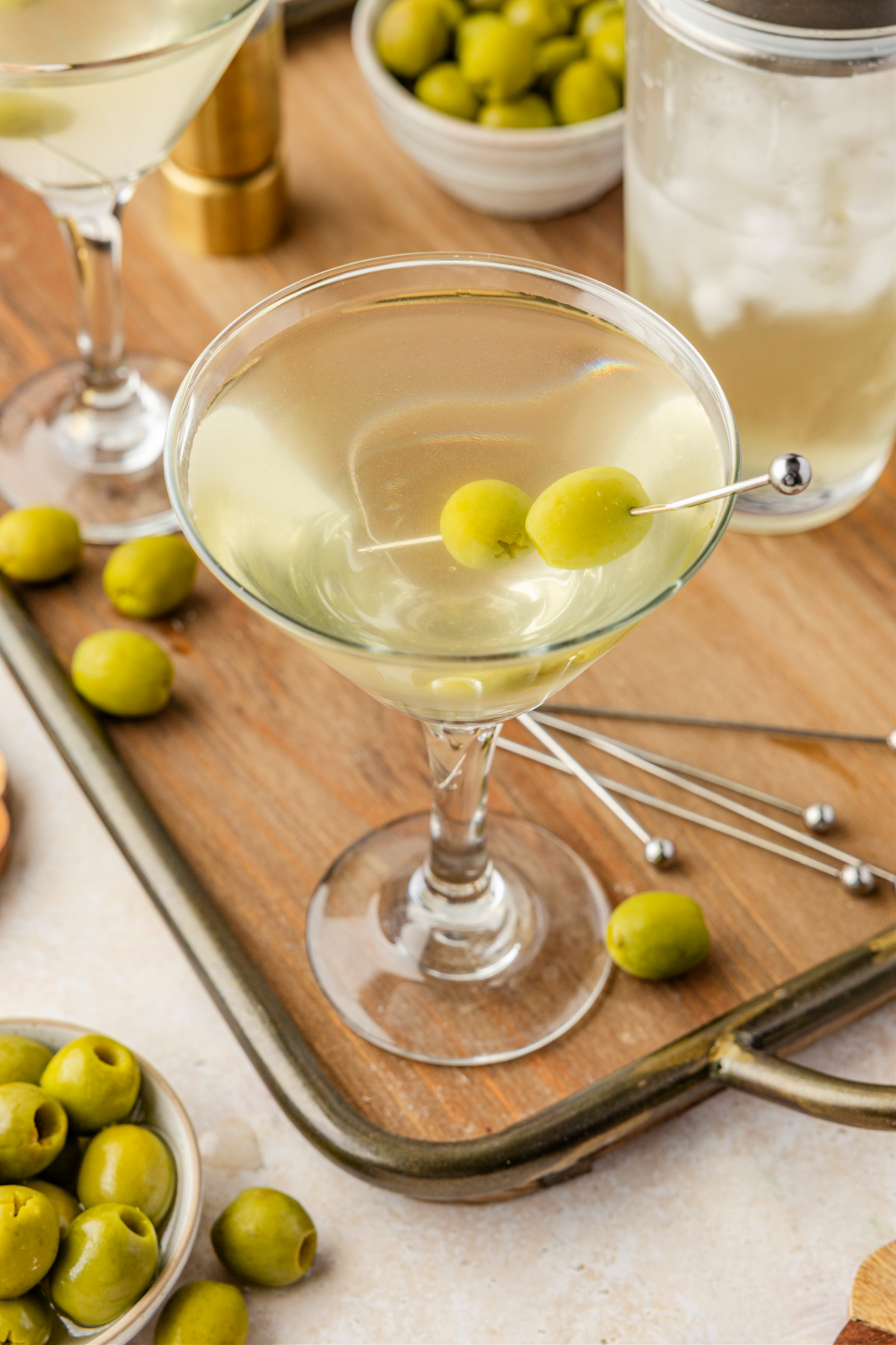 Overhead look at an extra dirty martini showing the cloudy, brine-forward cocktail and olive garnish. Top-down view of a briny extra dirty martini with two green olives skewered across the chilled glass.